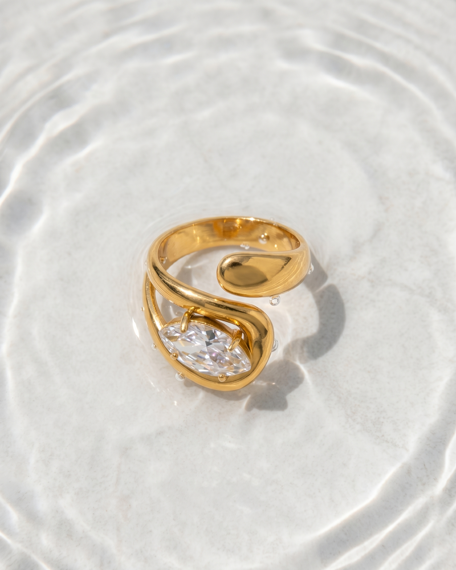 Gold ring with a clear gemstone on a white surface