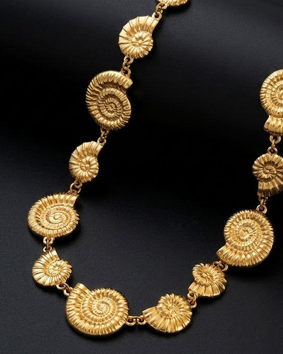 Gold necklace with intricate designs on a dark background