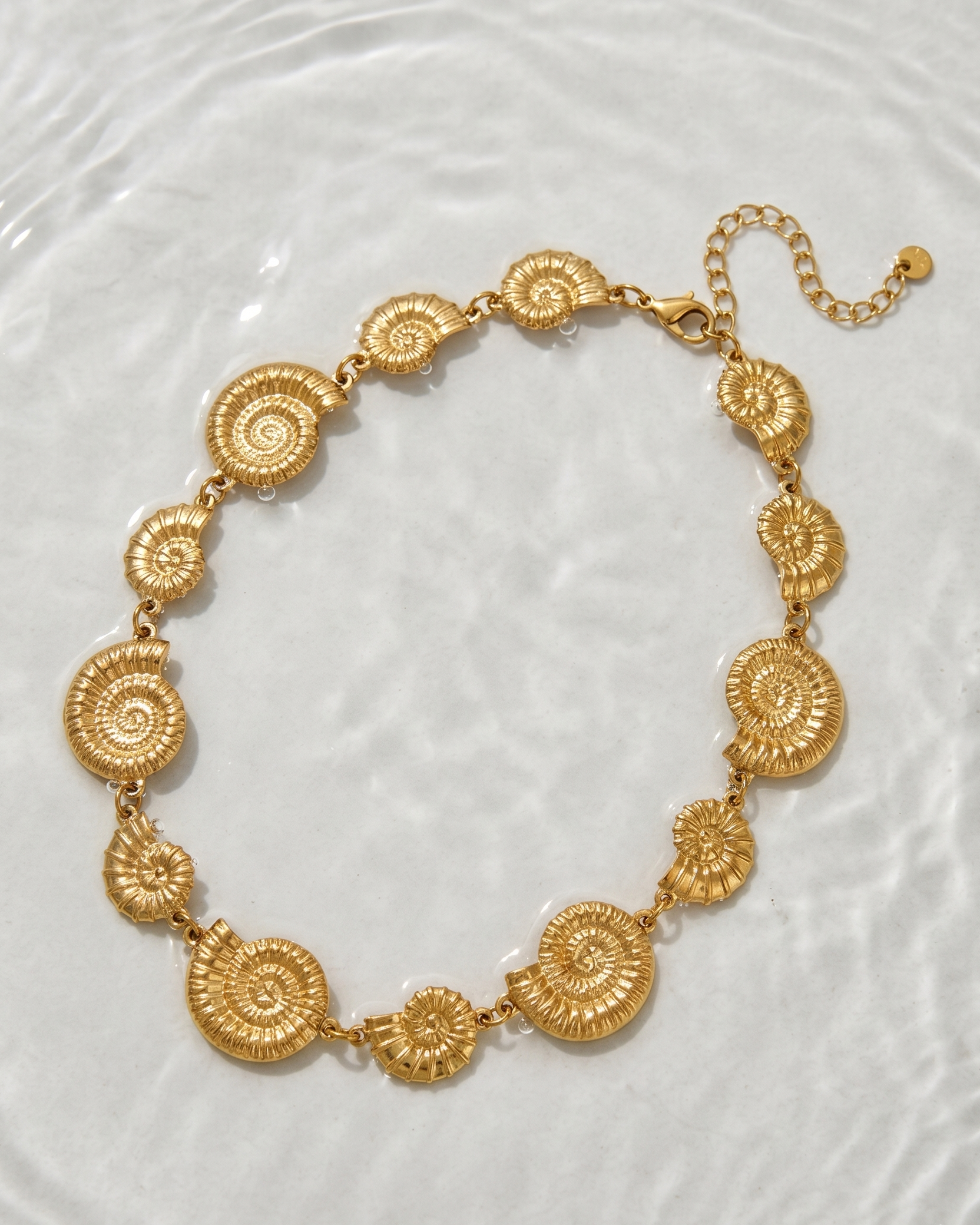 Gold necklace with circular patterns on a textured white background