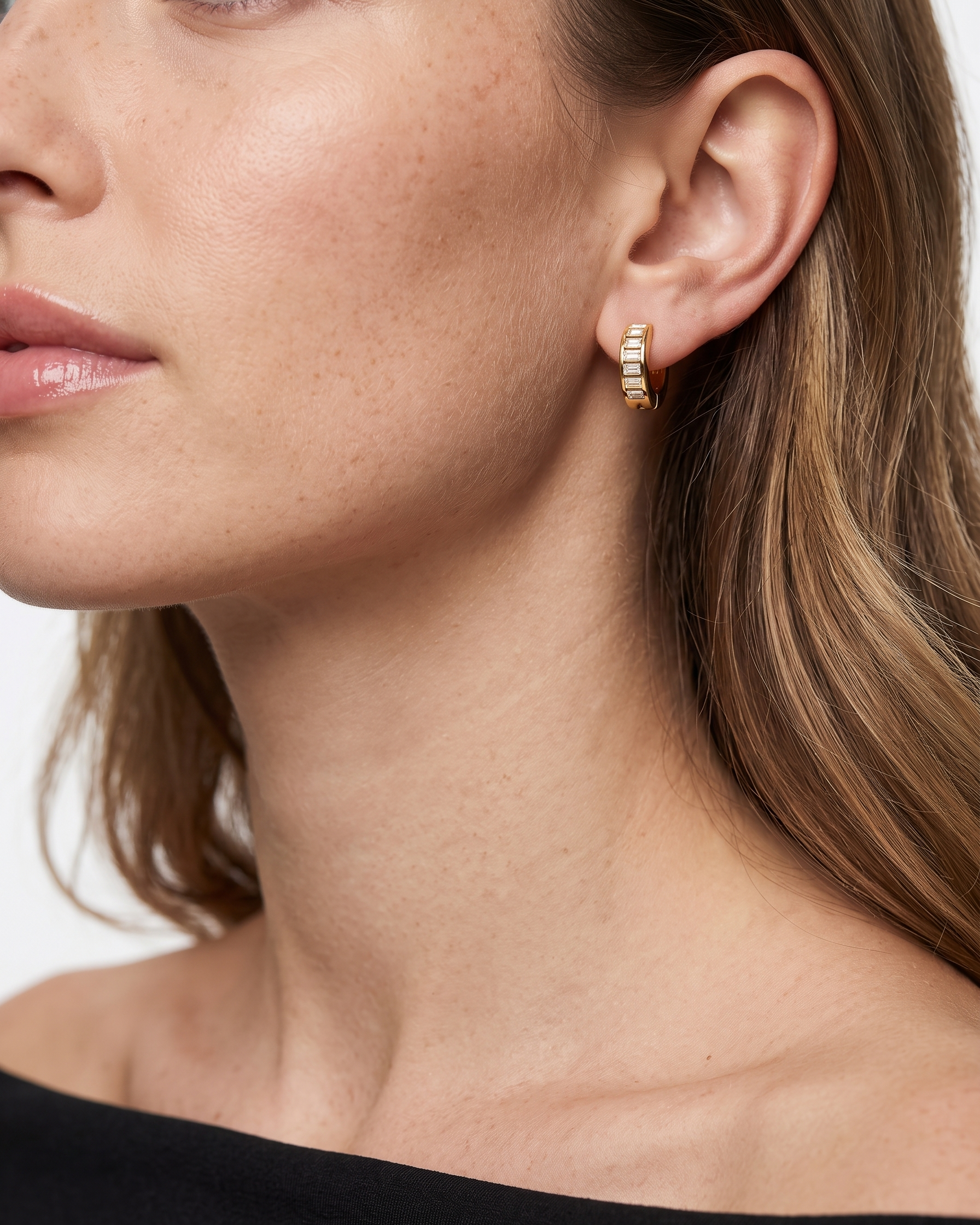Close-up of a woman wearing gold hoop earrings with a white background