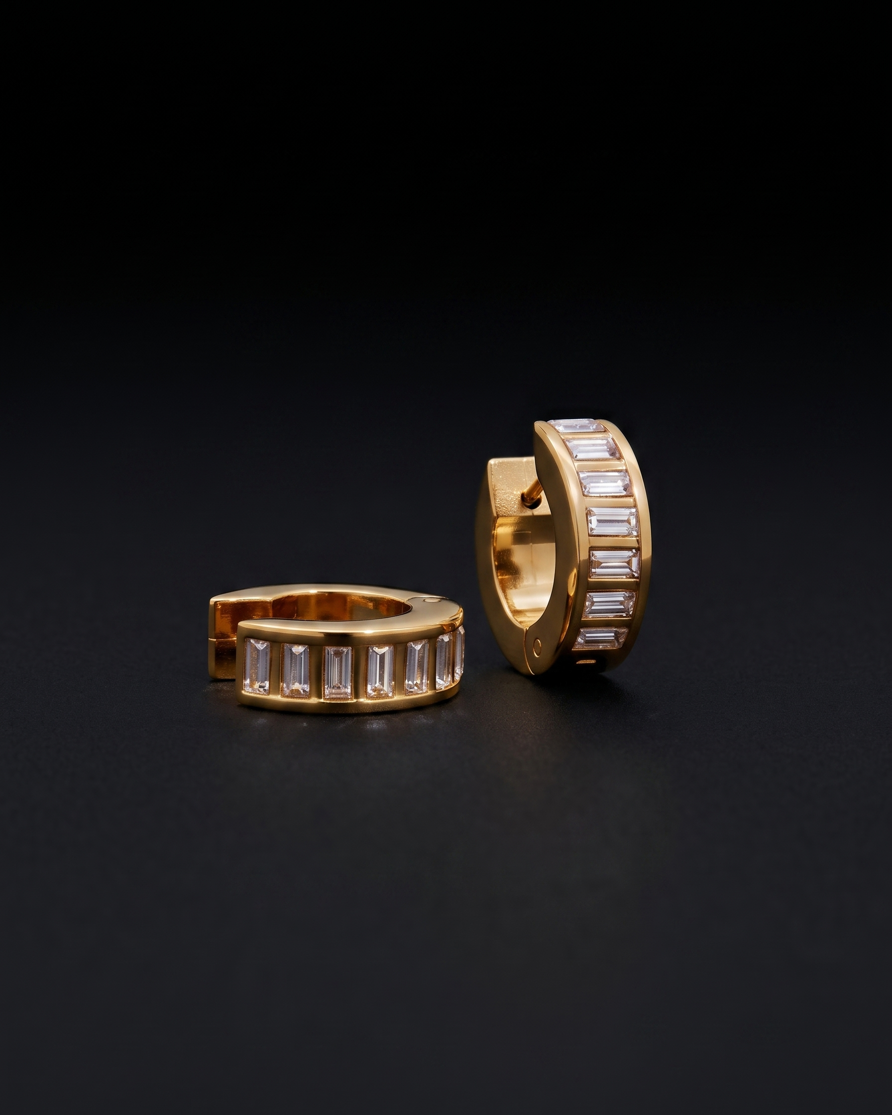 Gold hoop earrings with embedded stones on a black background