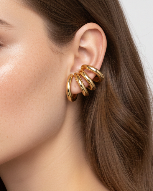 Woman wearing a gold hoop earring with a plain background