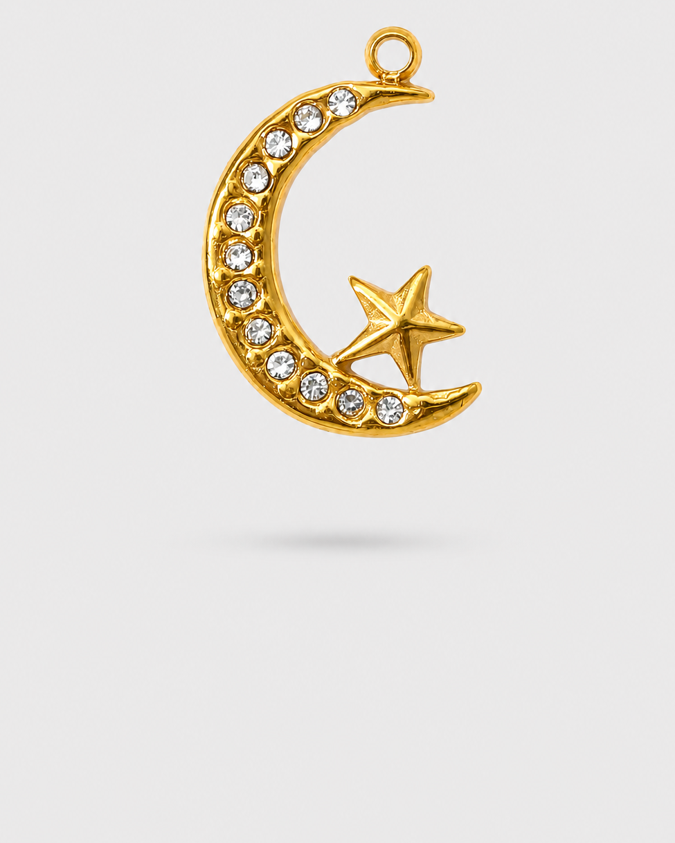 A gold crescent moon and star pendant charm, embellished with clear rhinestones along the curve of the crescent, shown against a light gray background.