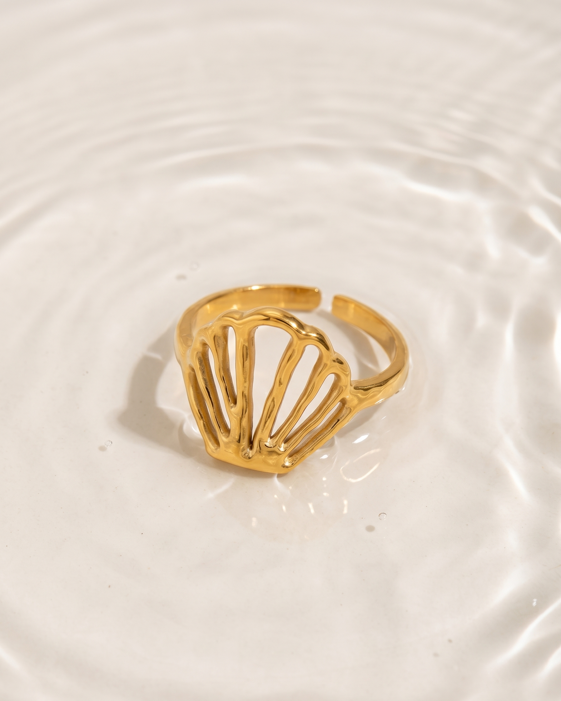 Gold ring with a shell design on a white plate