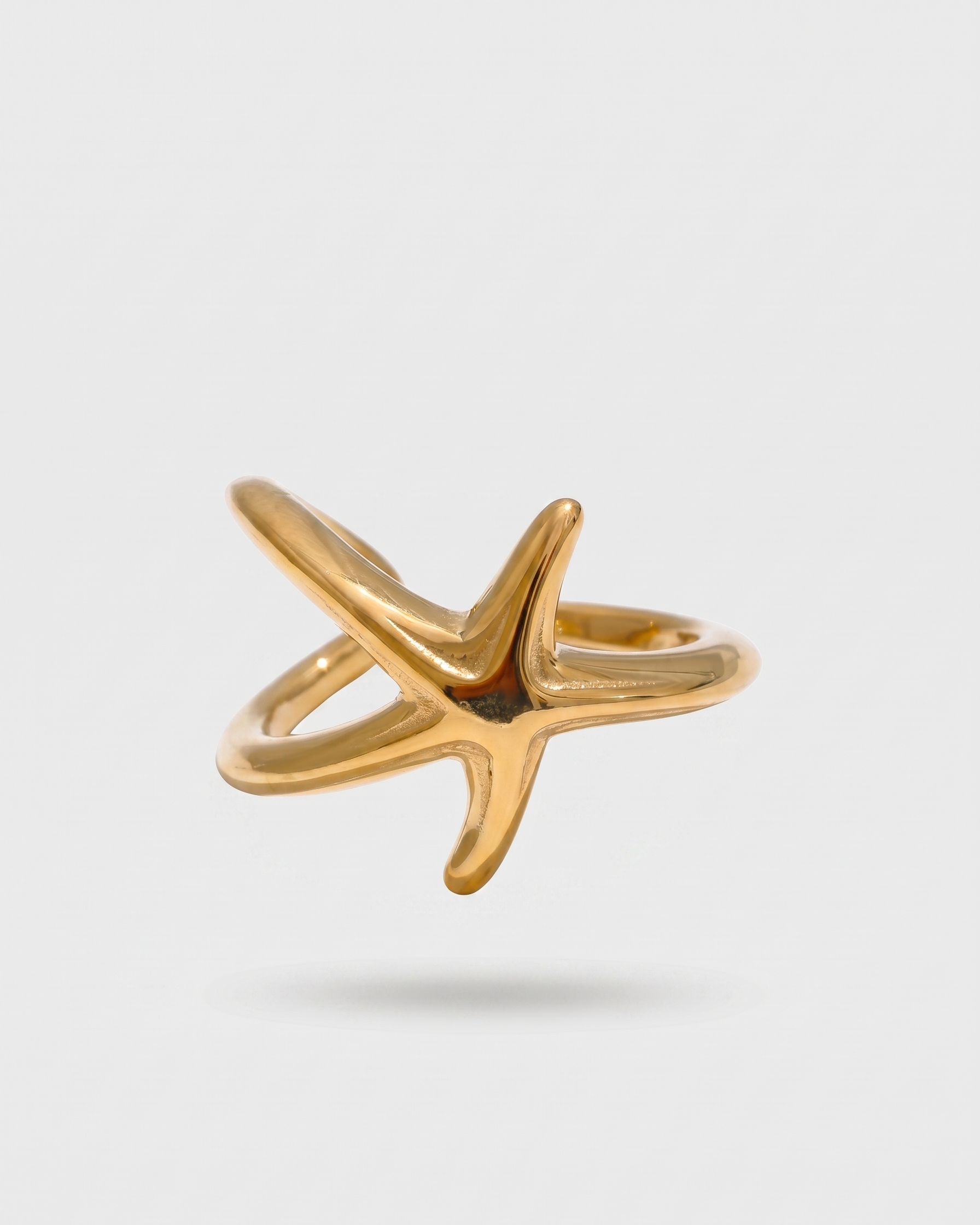 Gold star-shaped ring on a light gray background