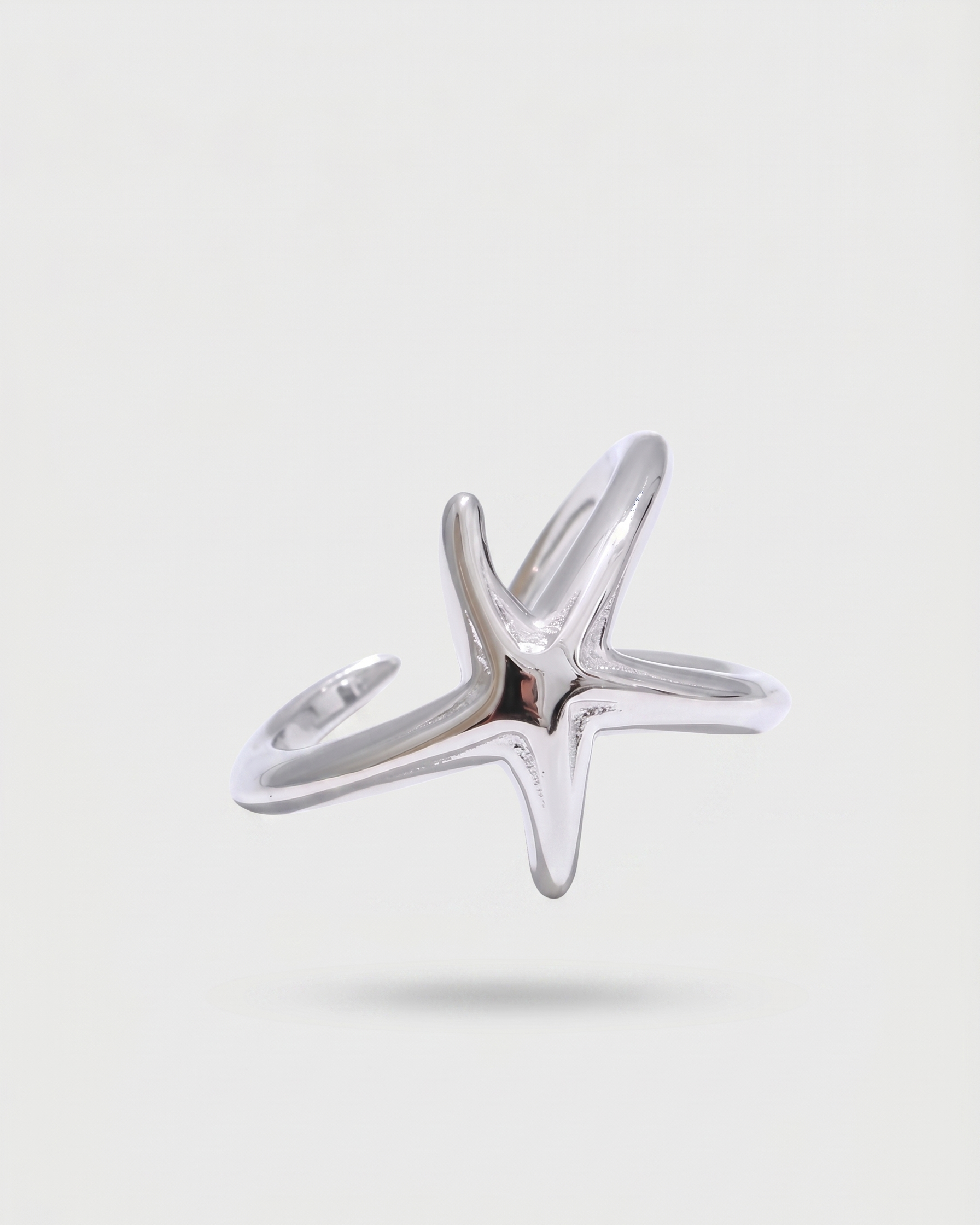 Silver star-shaped ring on a light gray background