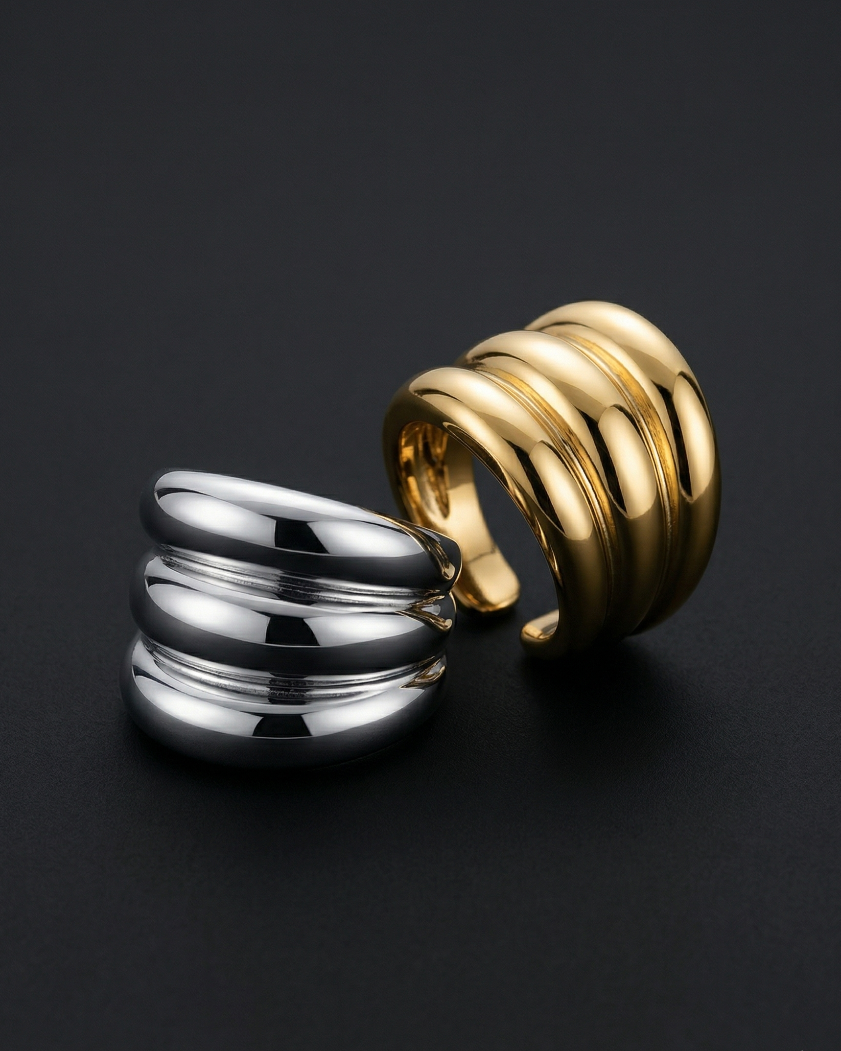 Gold and silver spiral cuff earrings on a black background