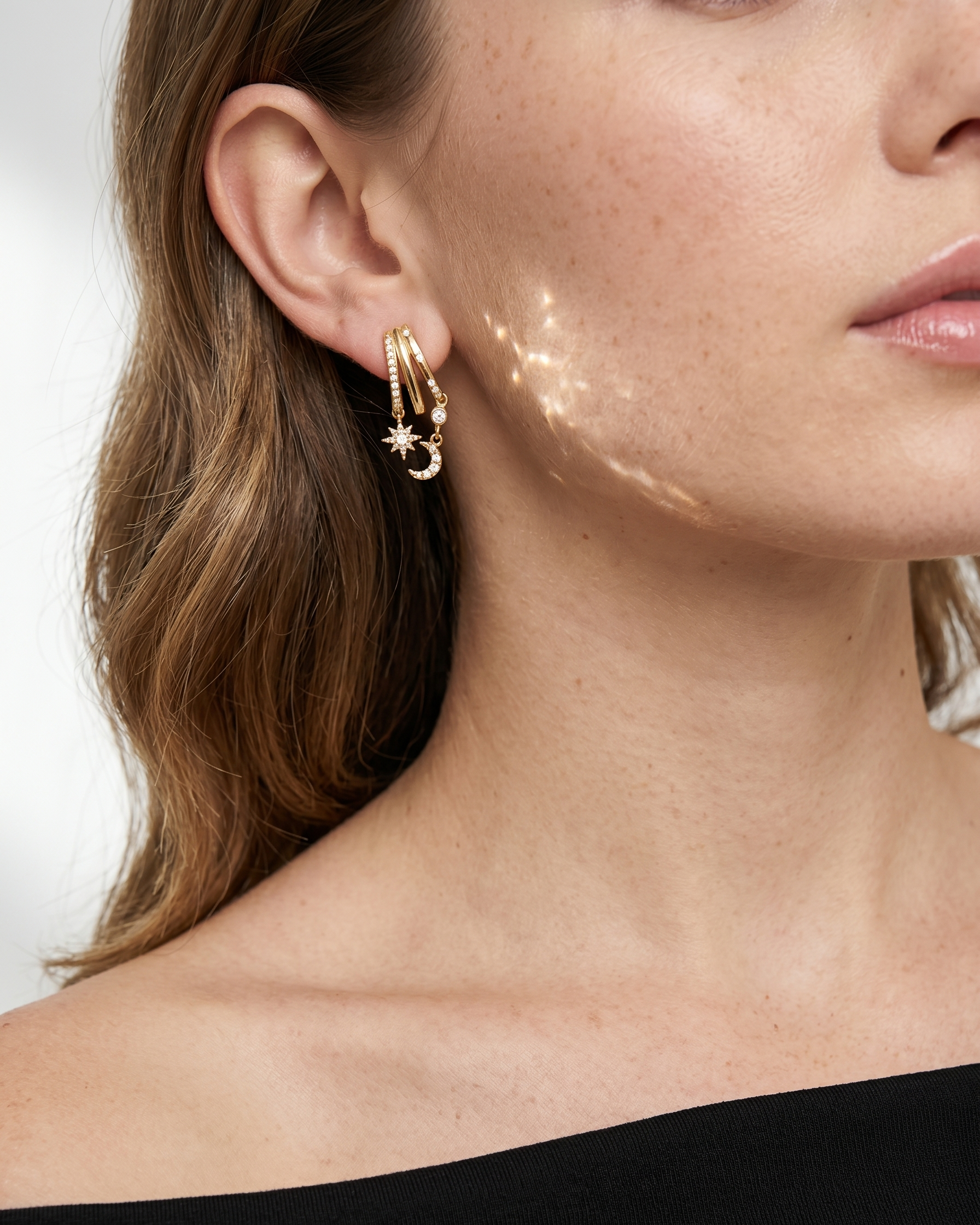 Close-up of a woman wearing gold hoop earrings with a neutral background
