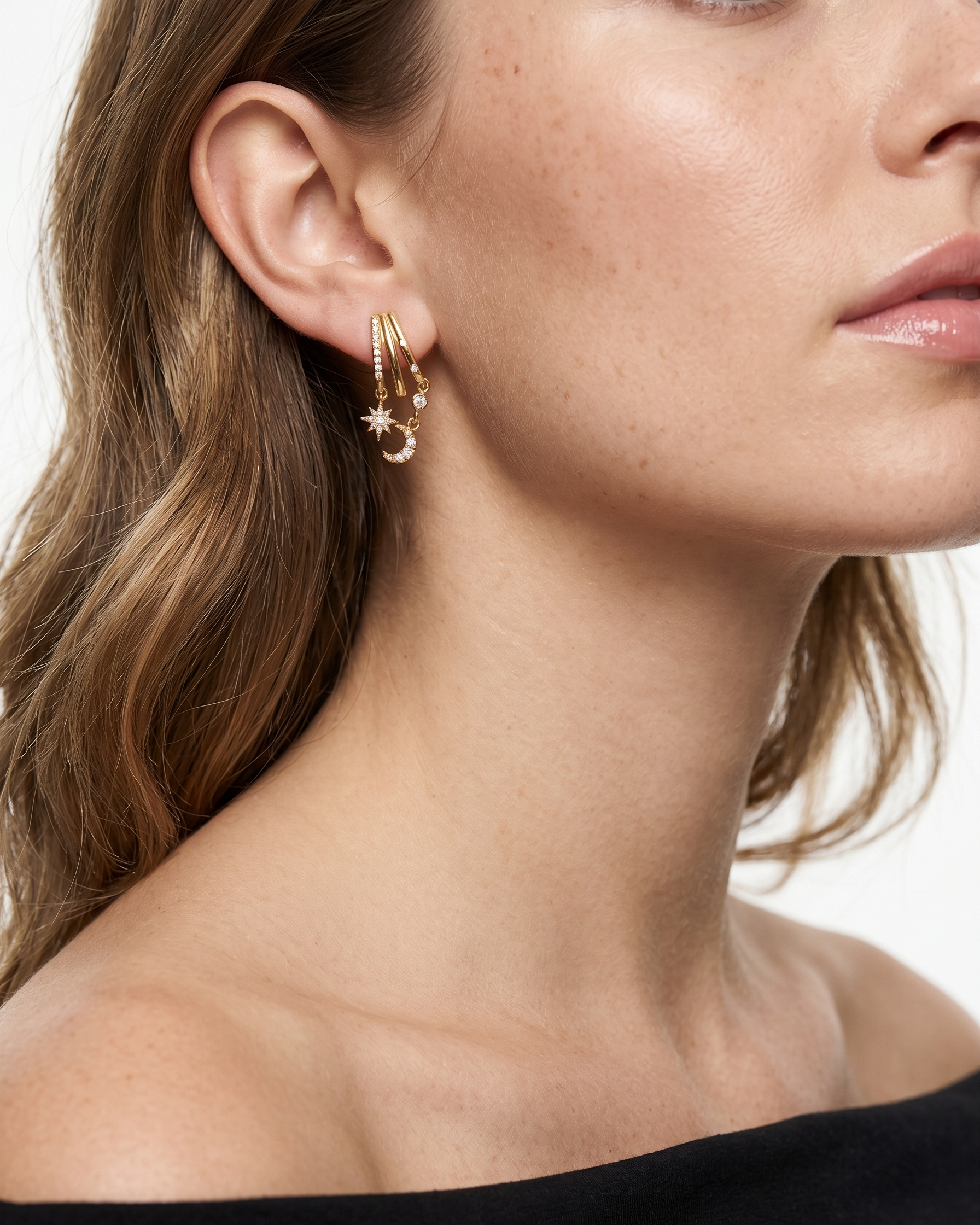 Close-up of a woman wearing gold hoop earrings with a plain background