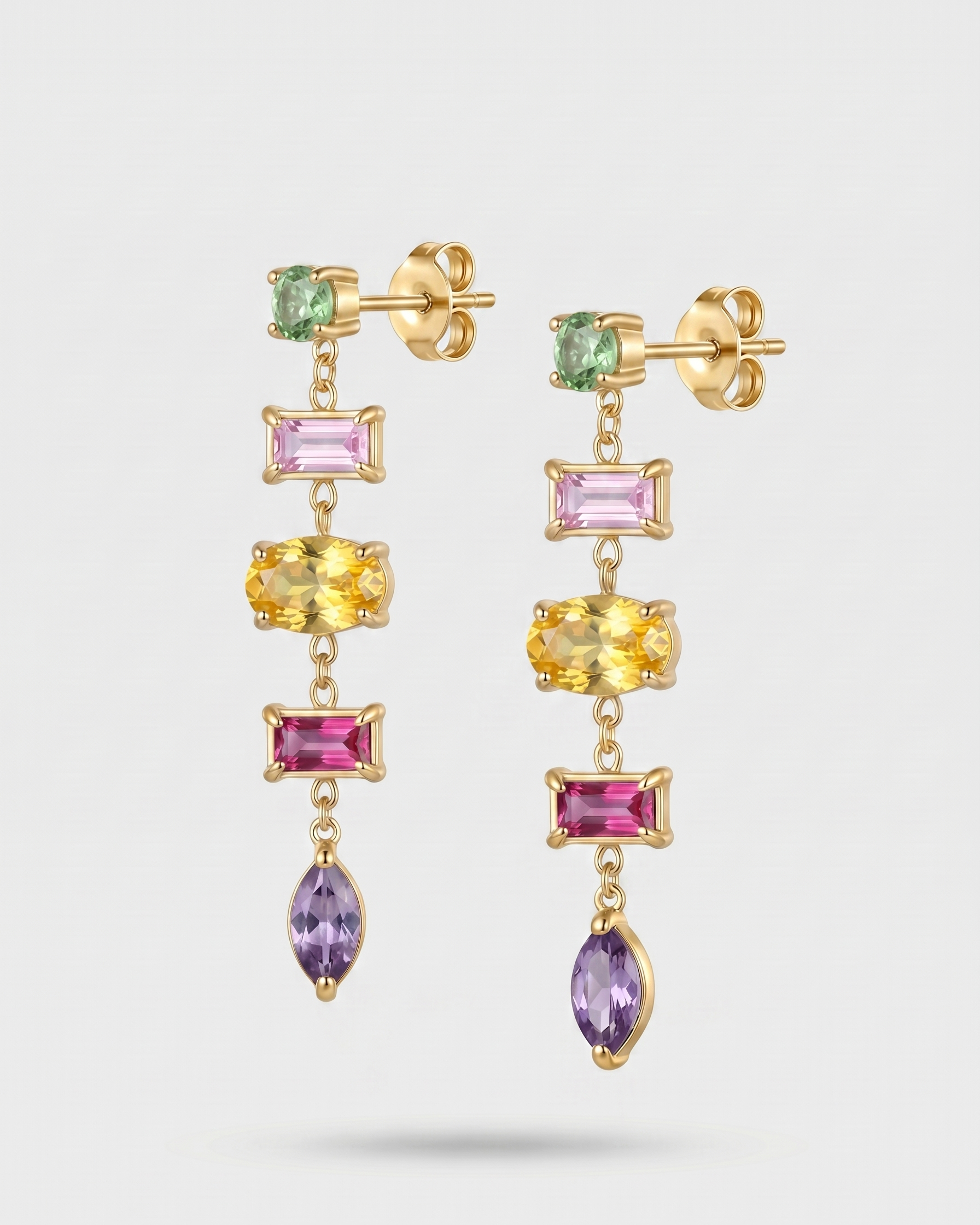 Gold earrings with multicolored gemstones on a white background