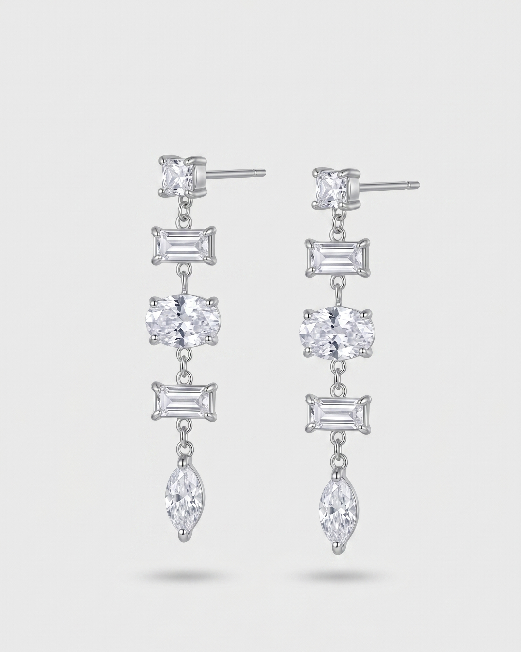 Pair of silver earrings with clear gemstones on a white background
