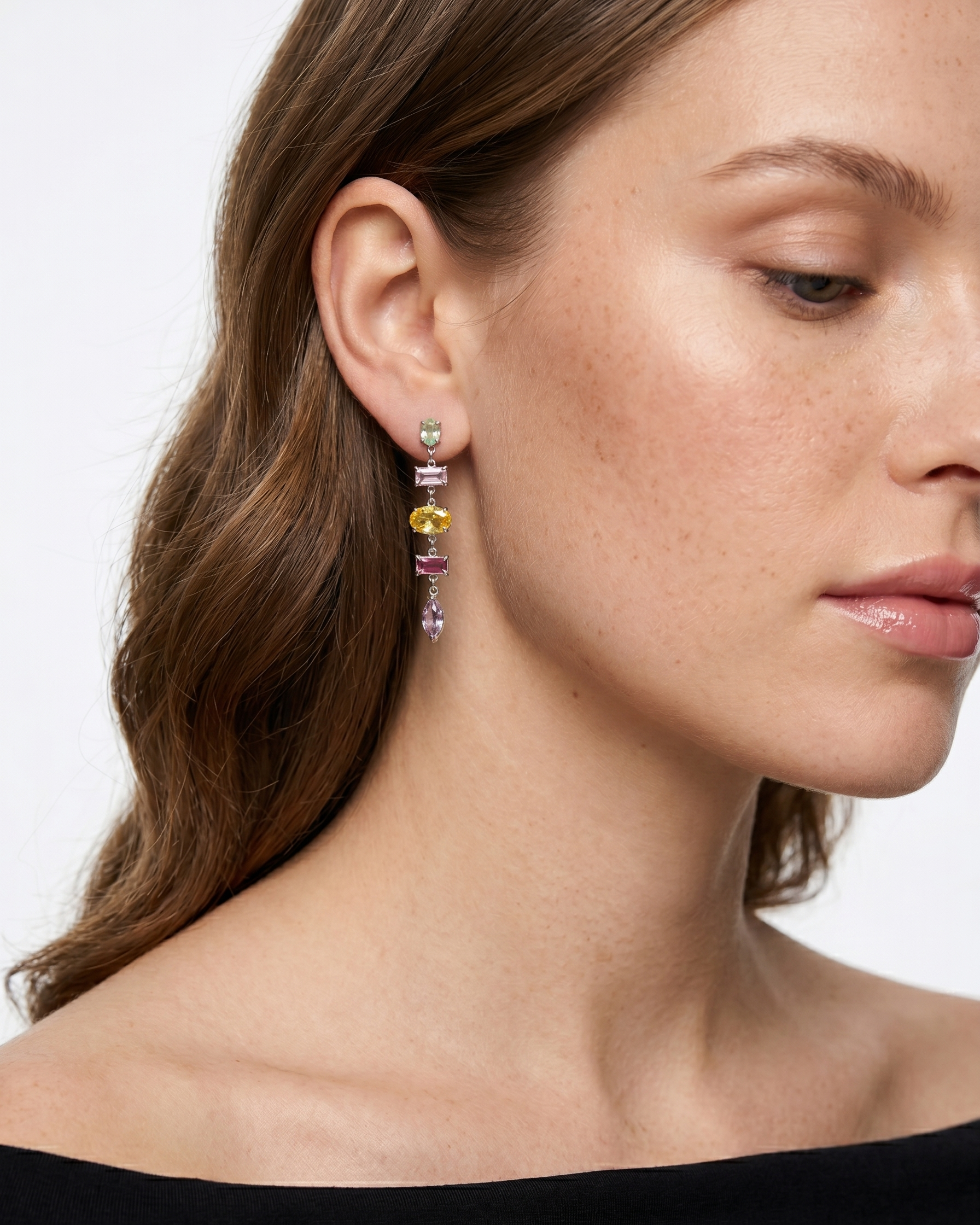 Close-up of a woman wearing colorful earrings with a neutral background
