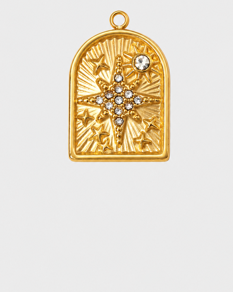 A gold pendant with an arched top and a starburst design, featuring a central cluster of clear gemstones and a small clear stone near the top right, shown on a light gray background.
