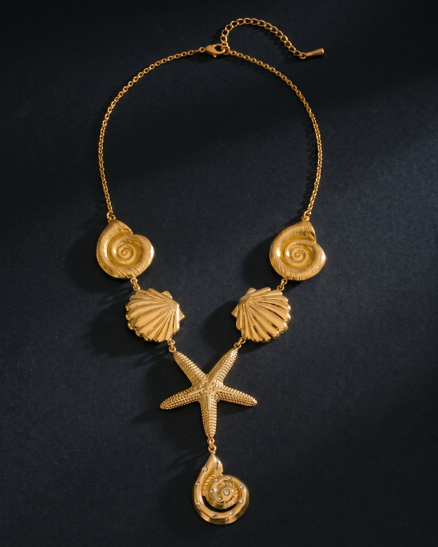 Gold necklace with shell and starfish pendants on a black background