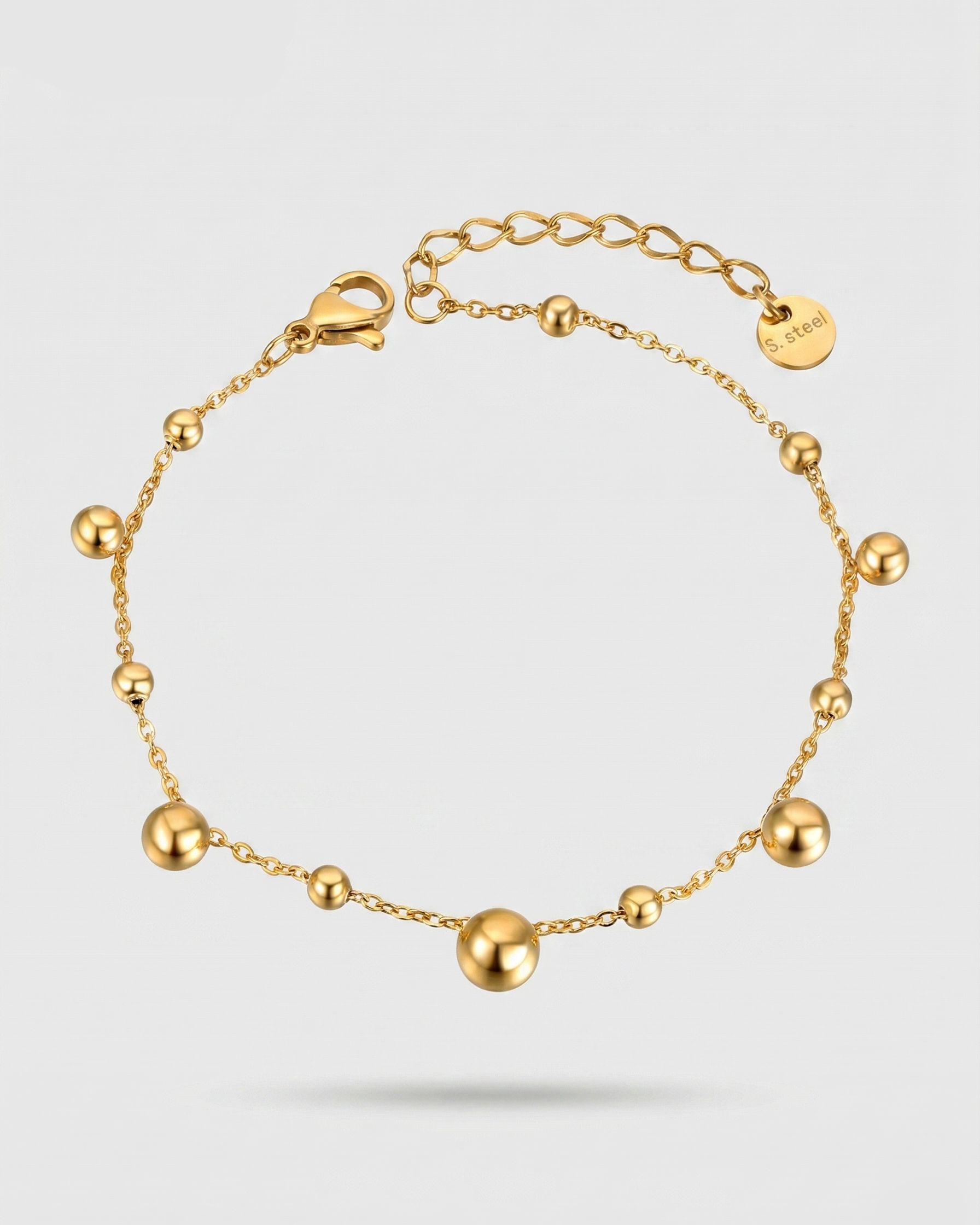 Gold bracelet with spherical beads on a white background
