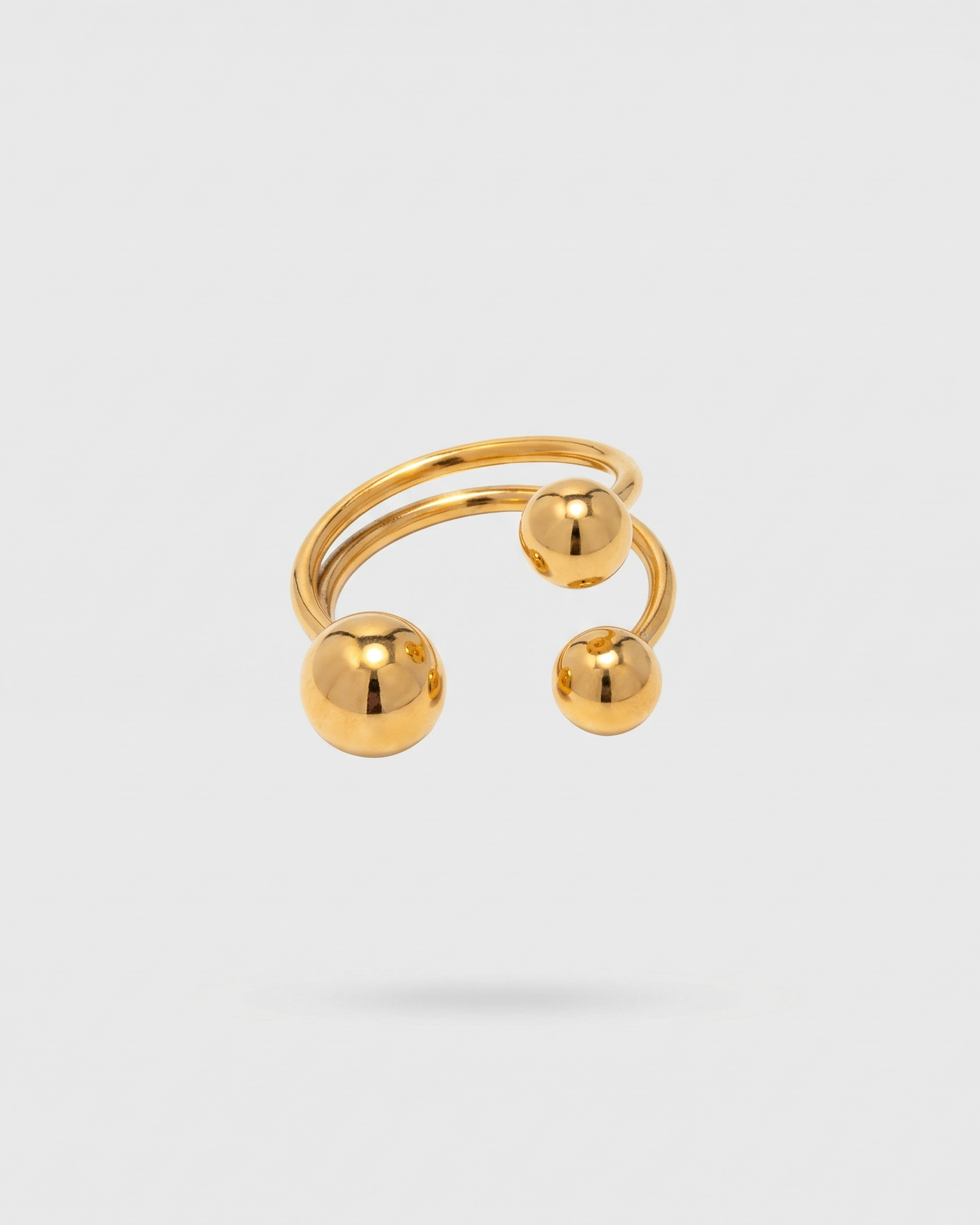 Gold ear cuff with spherical designs on a white background