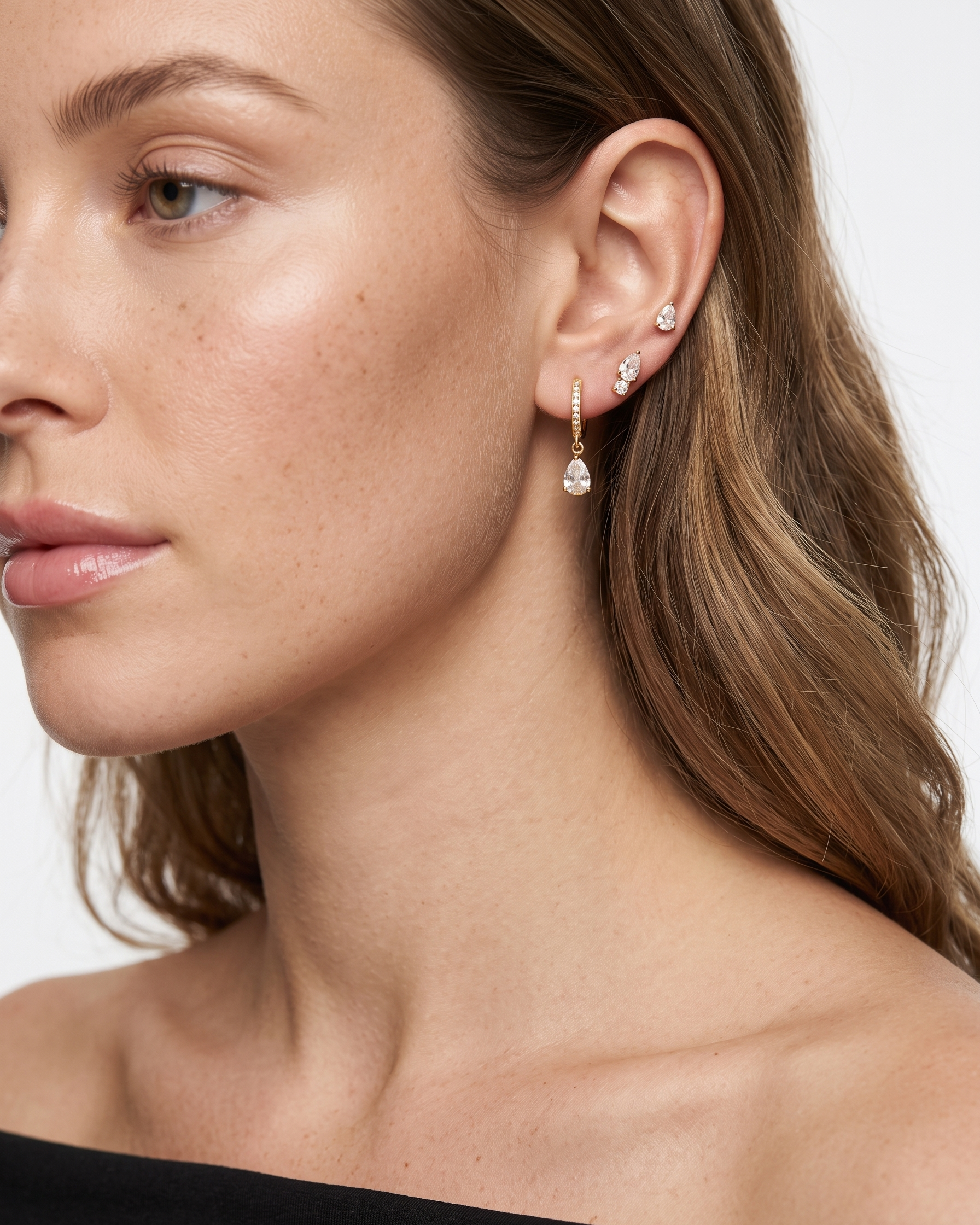 Close-up of a woman wearing diamond earrings with a neutral background