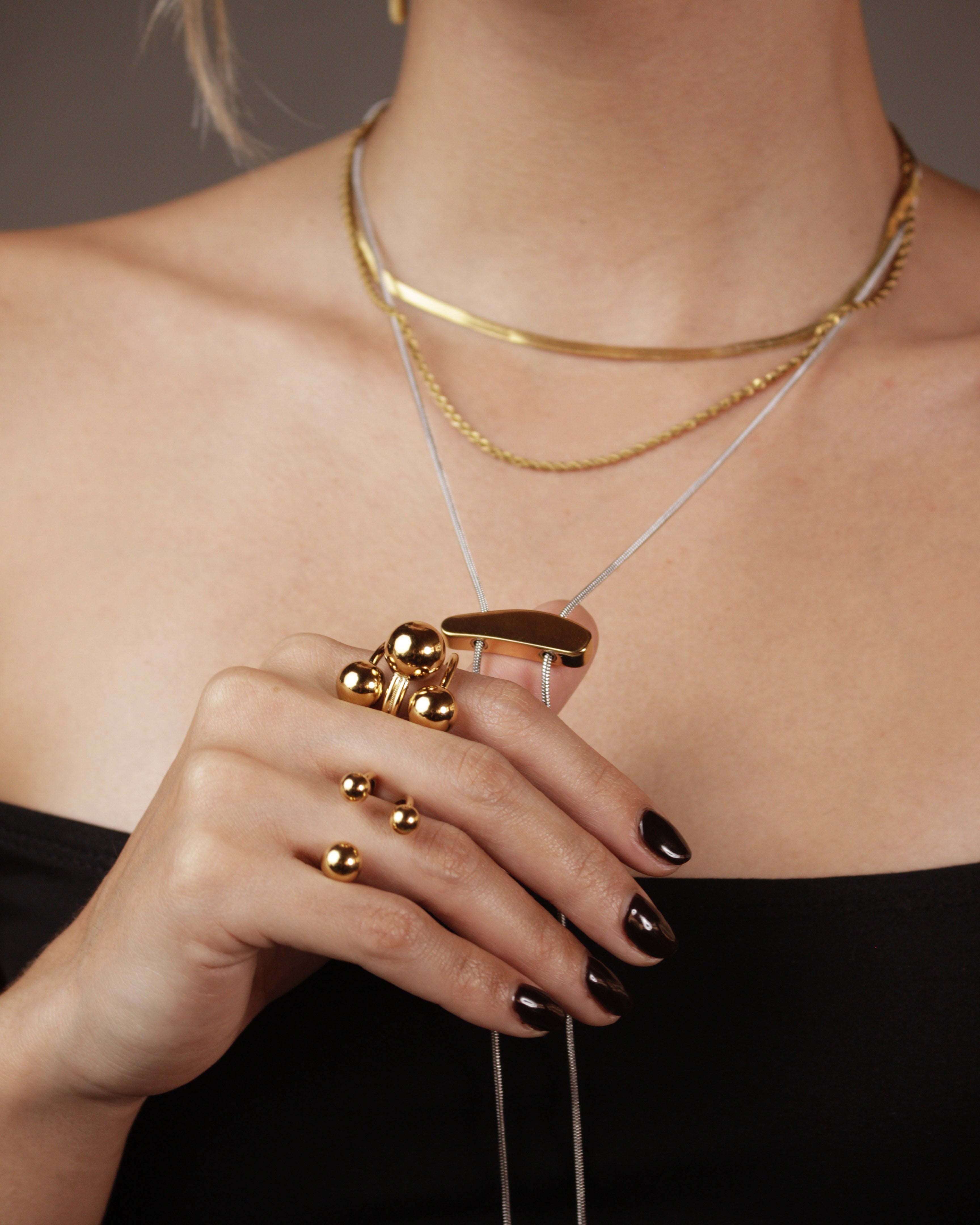 Close-up of a person wearing gold jewelry including a necklace, bracelet, and rings.