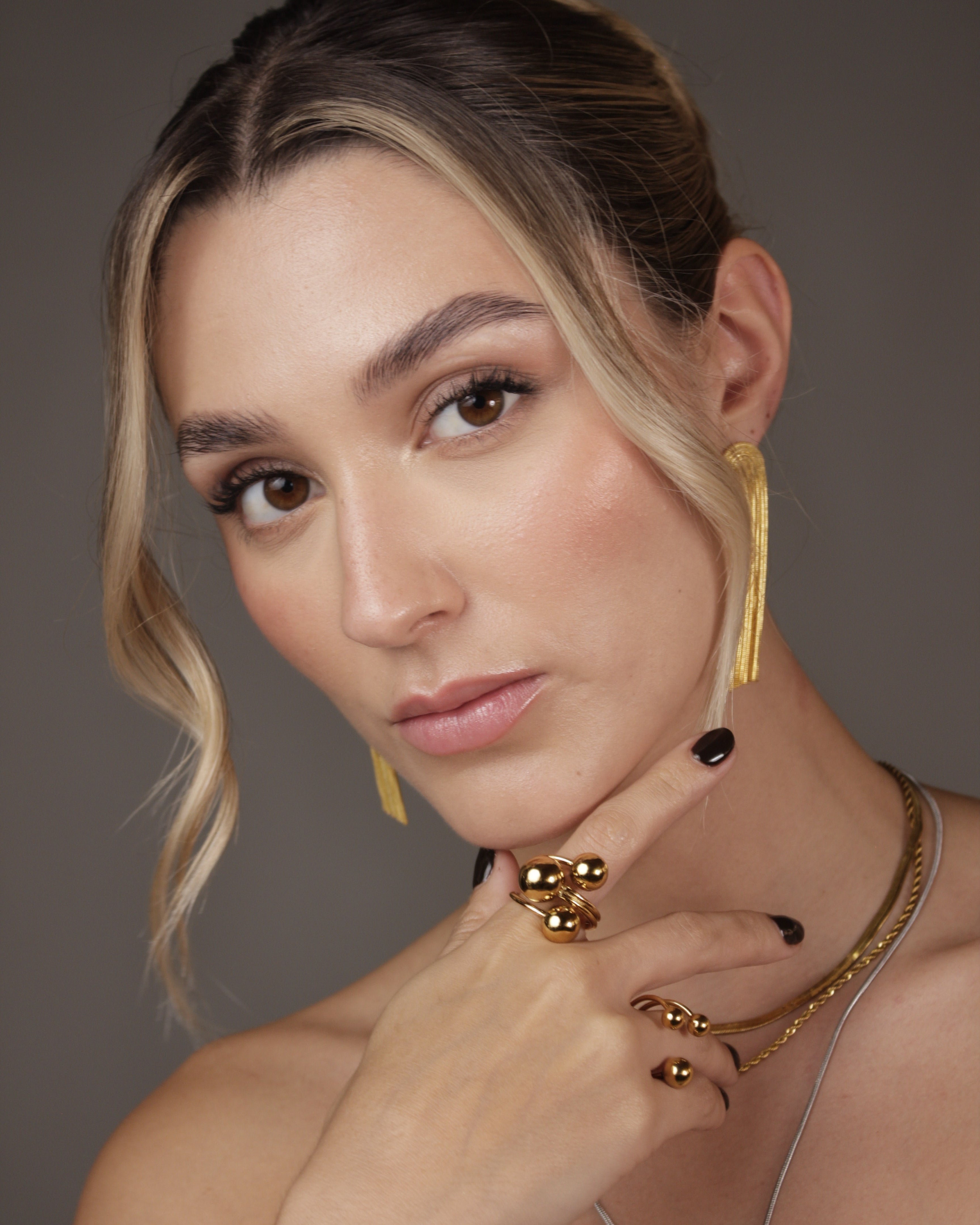 Woman wearing gold jewelry against a neutral background