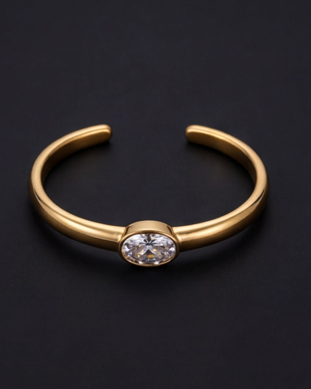 Gold bracelet with a central gemstone on a black background
