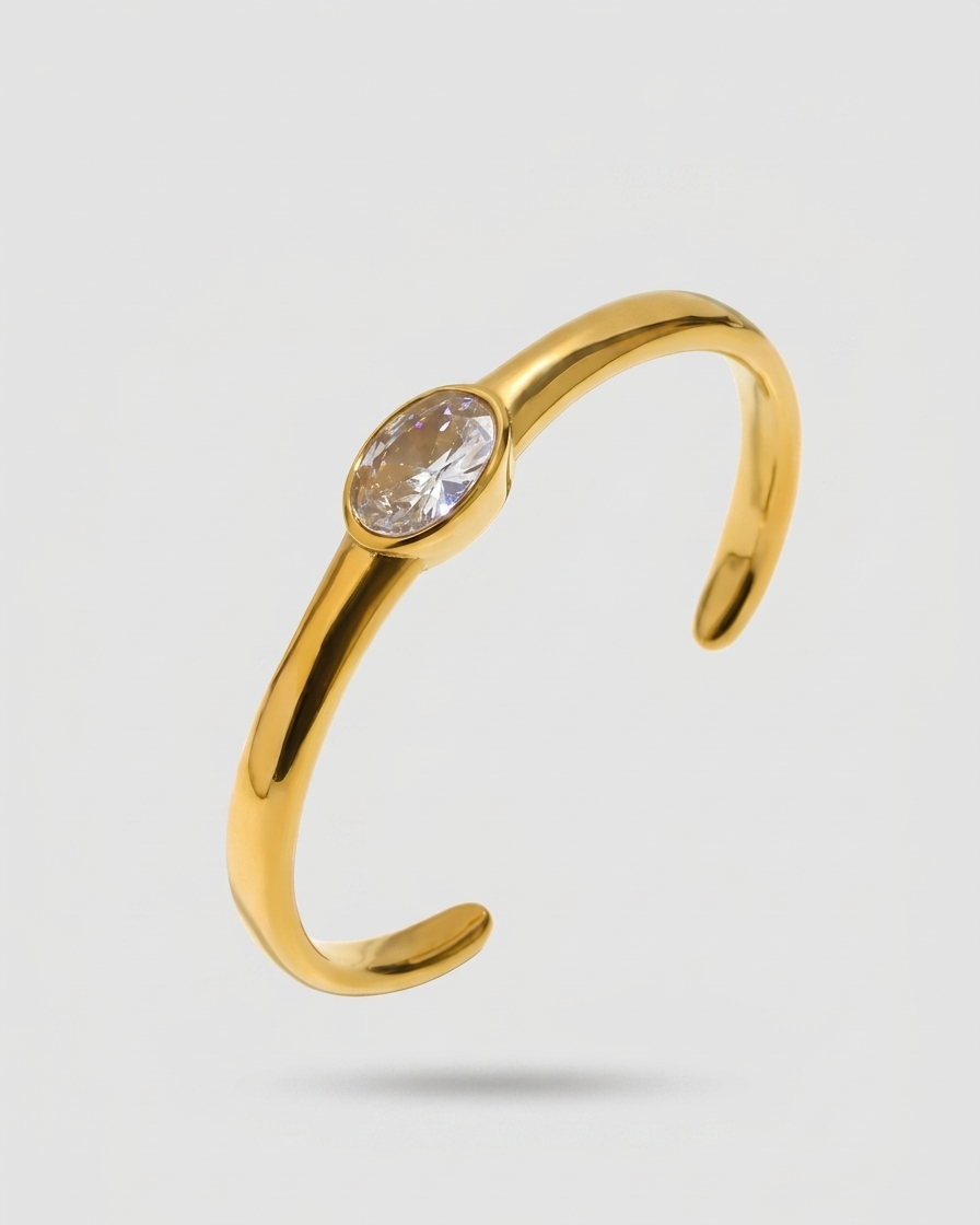 Gold open ring with a clear gemstone on a light gray background