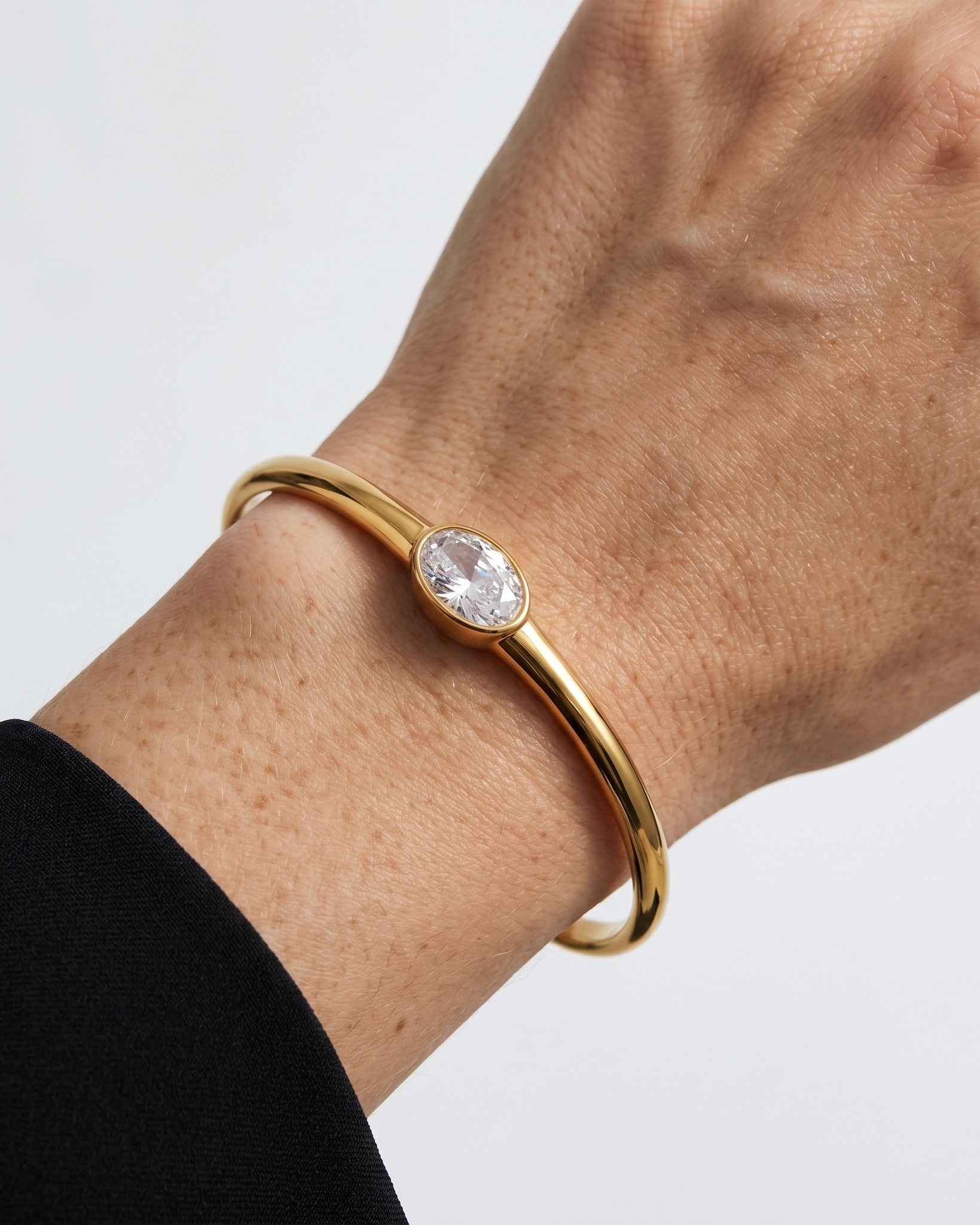Gold bracelet with a diamond on a wrist against a white background