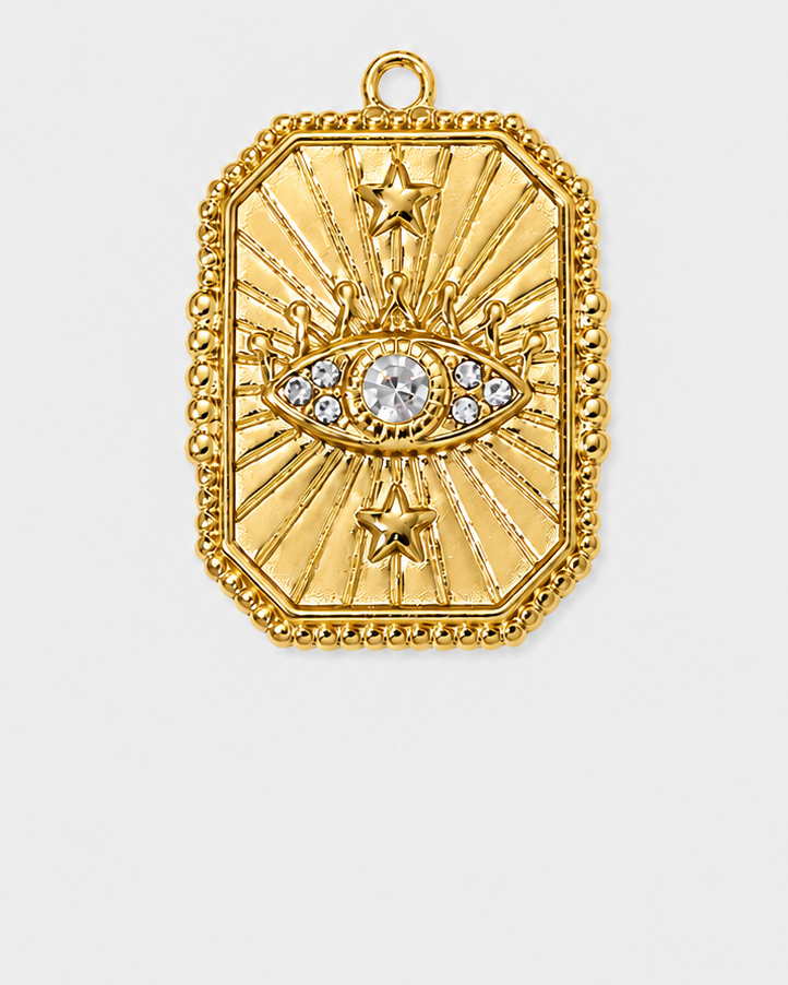 A gold-toned rectangular pendant with a sunburst design, two stars, and an eye motif set with clear stones, shown on a light gray background.