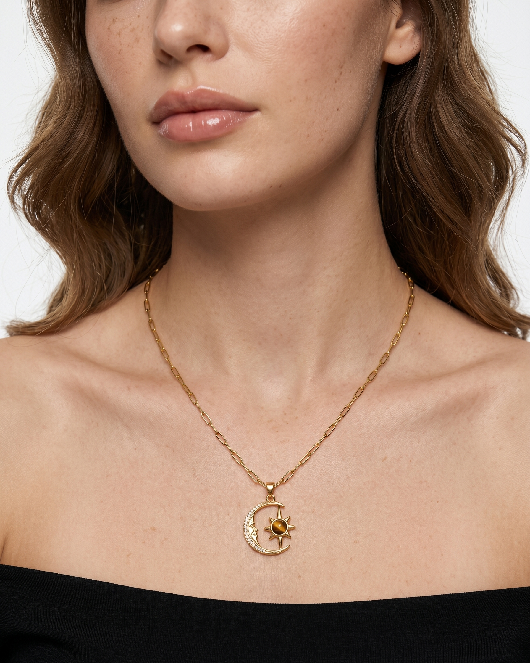 Close-up of a woman wearing a gold necklace with a pendant on a plain background