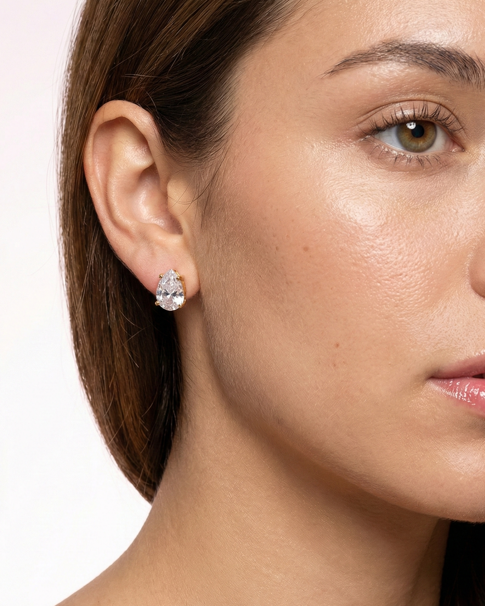Close-up of a woman wearing a diamond earring with a plain background