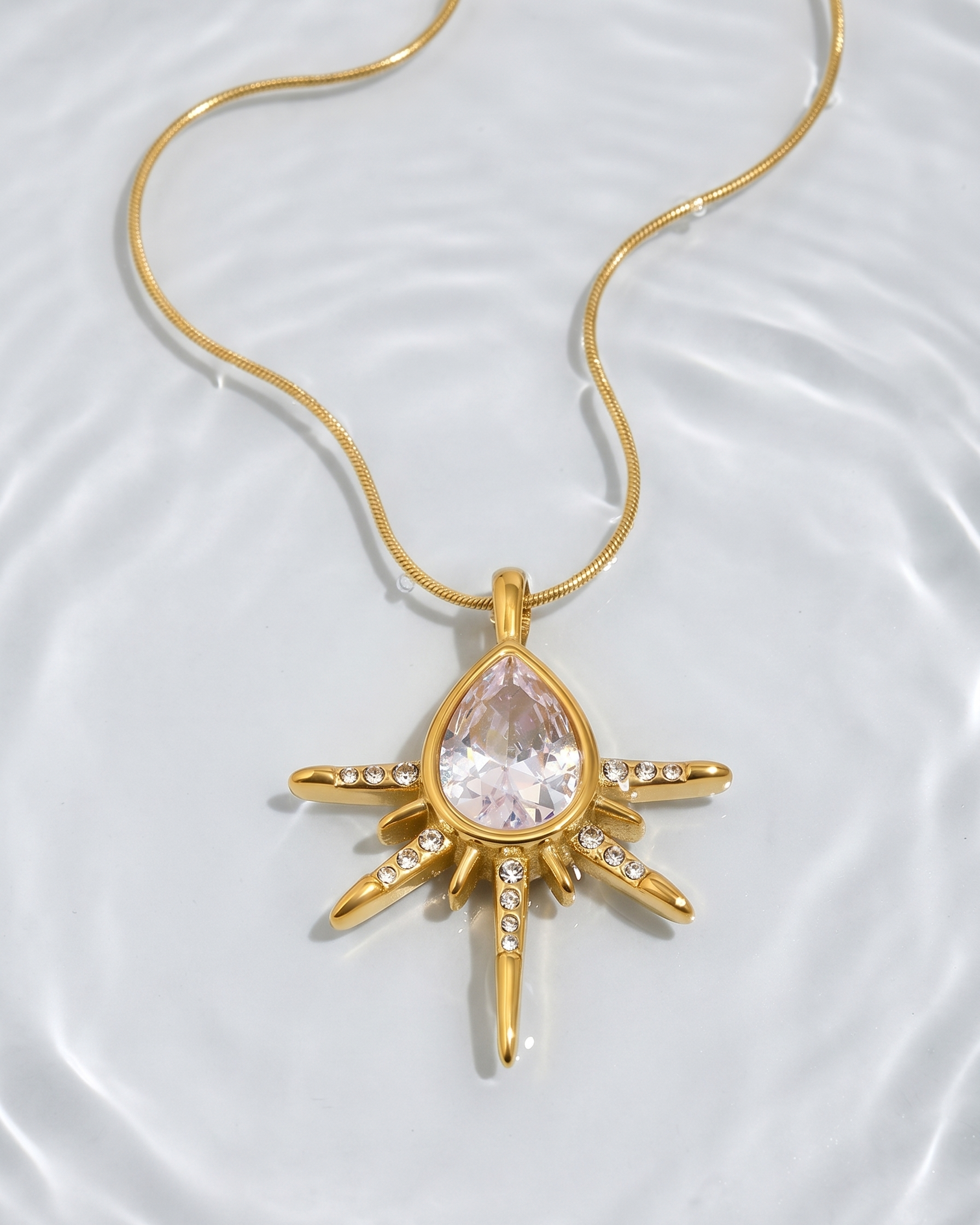 Gold necklace with a teardrop-shaped pendant on a white background