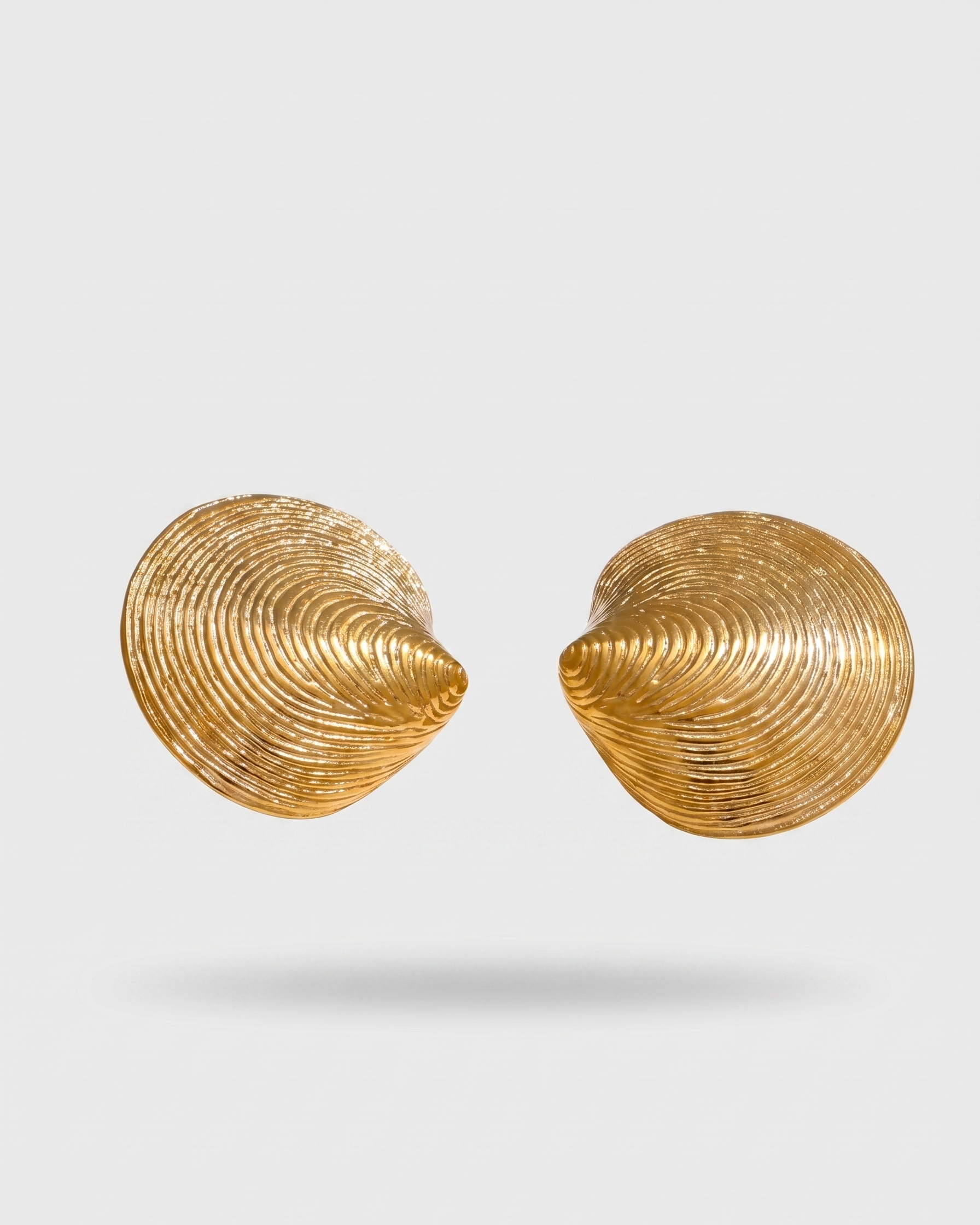 Pair of gold shell-shaped earrings on a light gray background