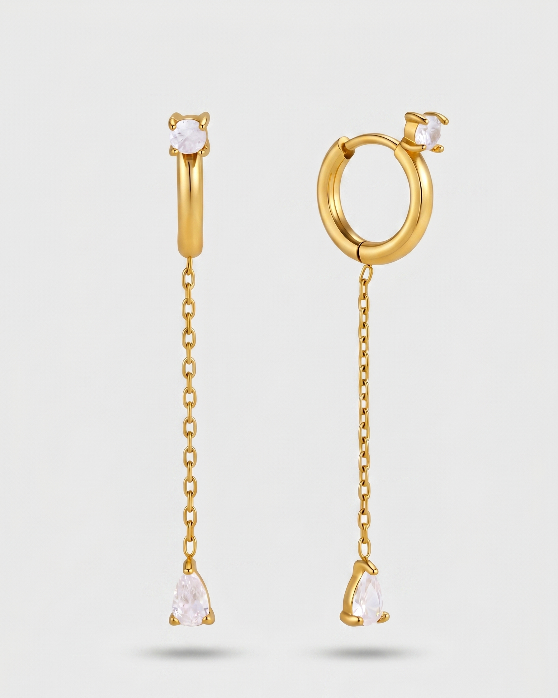 Gold hoop earrings with chain drops on a light gray background