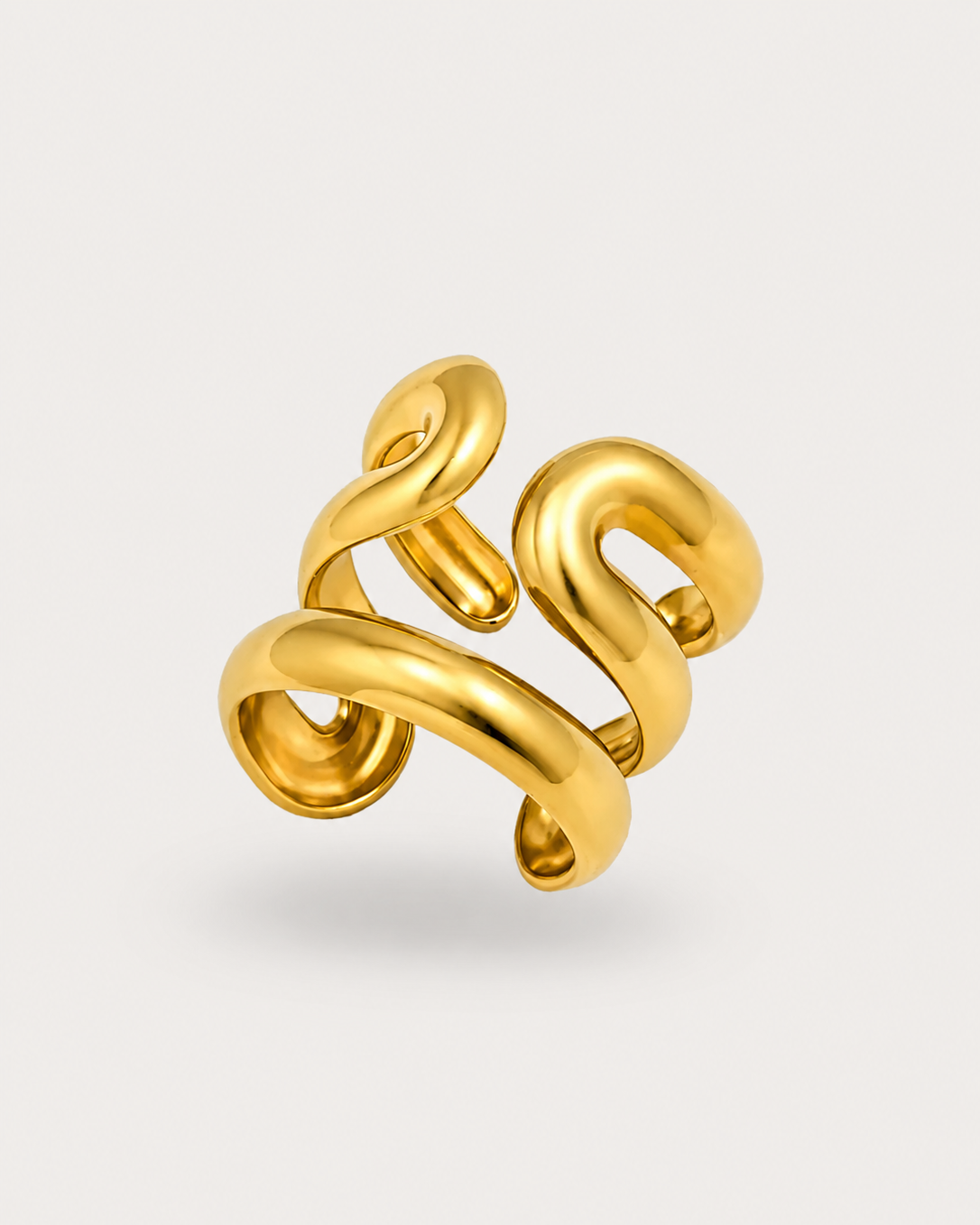 A polished gold ring with a sculptural, intertwined loop design, shown on a clean, light off-white background.