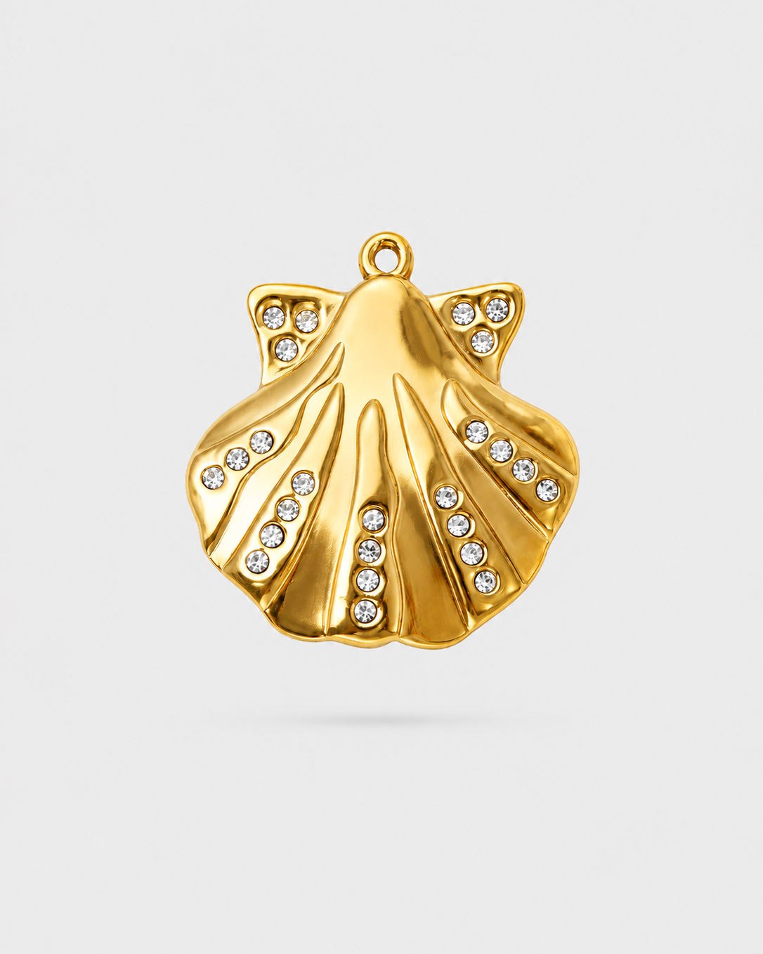A gold-toned shell-shaped pendant charm embellished with small clear rhinestones, shown on a light gray background.