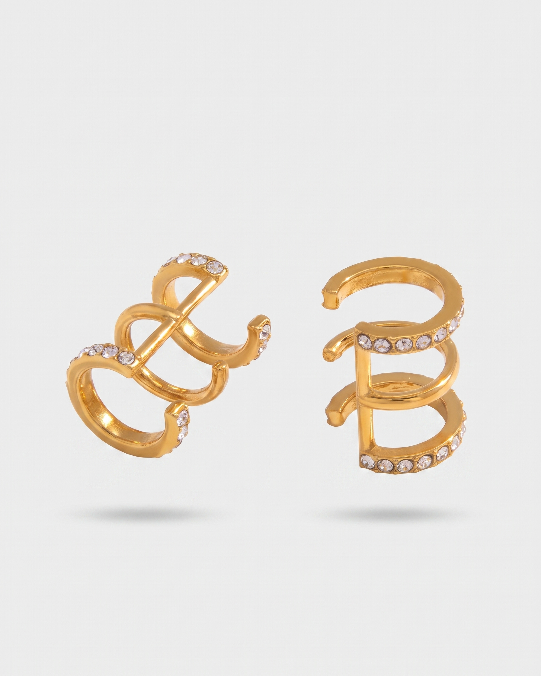 Gold spiral earrings with embedded stones on a light gray background
