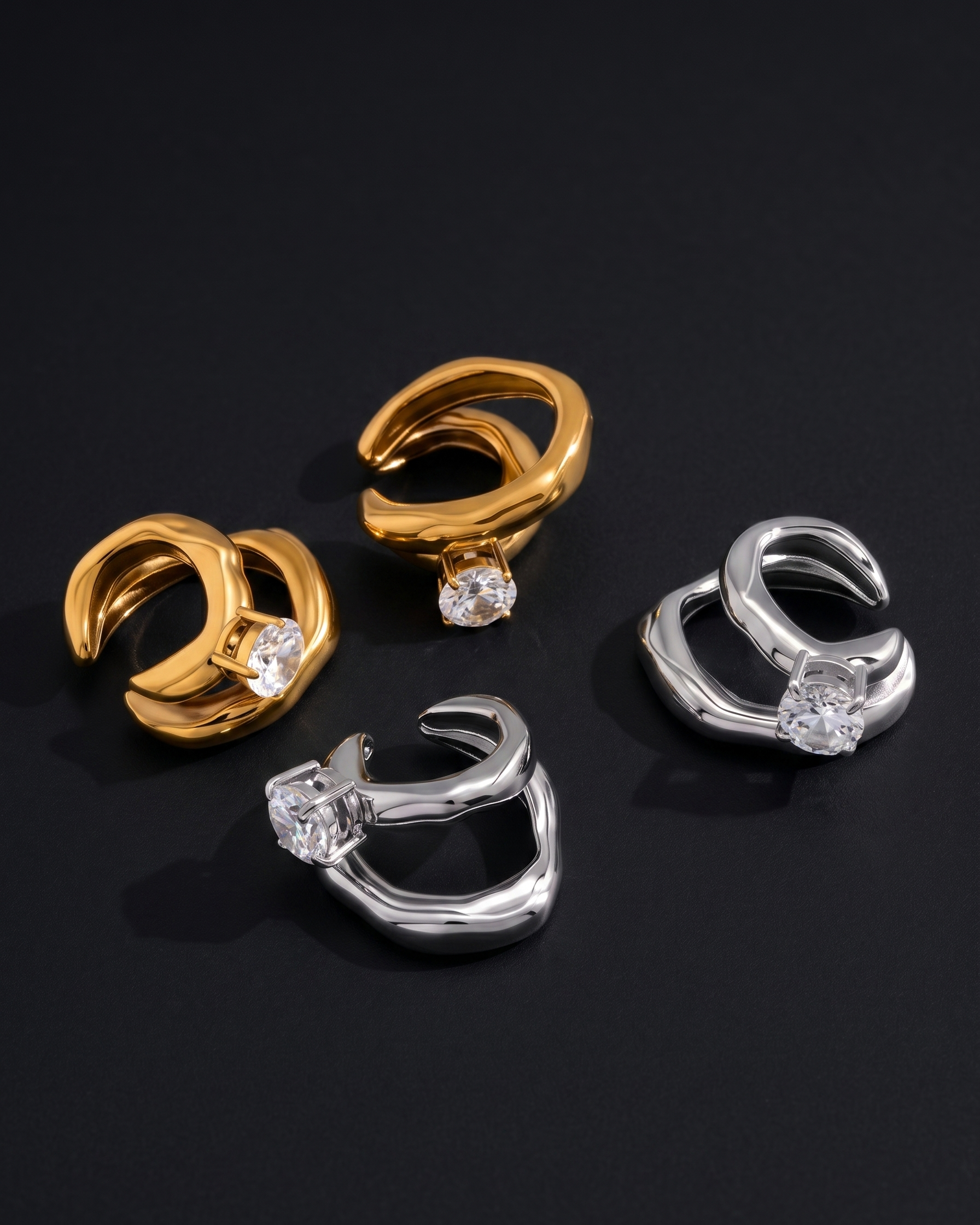 Pair of gold and silver hoop earrings with clear gemstones on a black background
