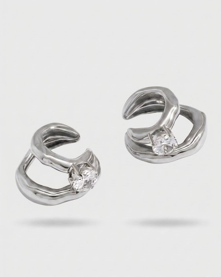 Pair of silver hoop earrings with clear gemstones on a light gray background