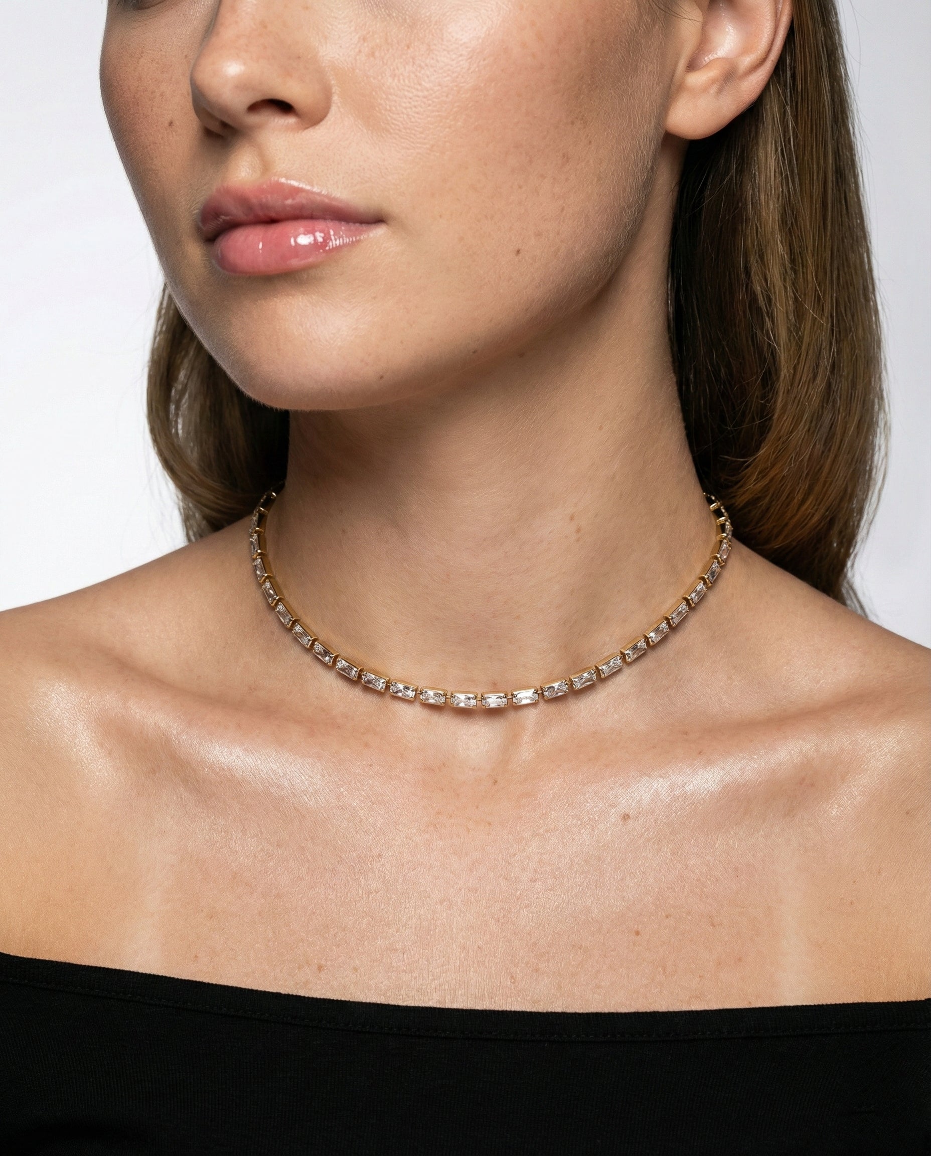 Close-up of a person wearing a delicate chain necklace against a neutral background