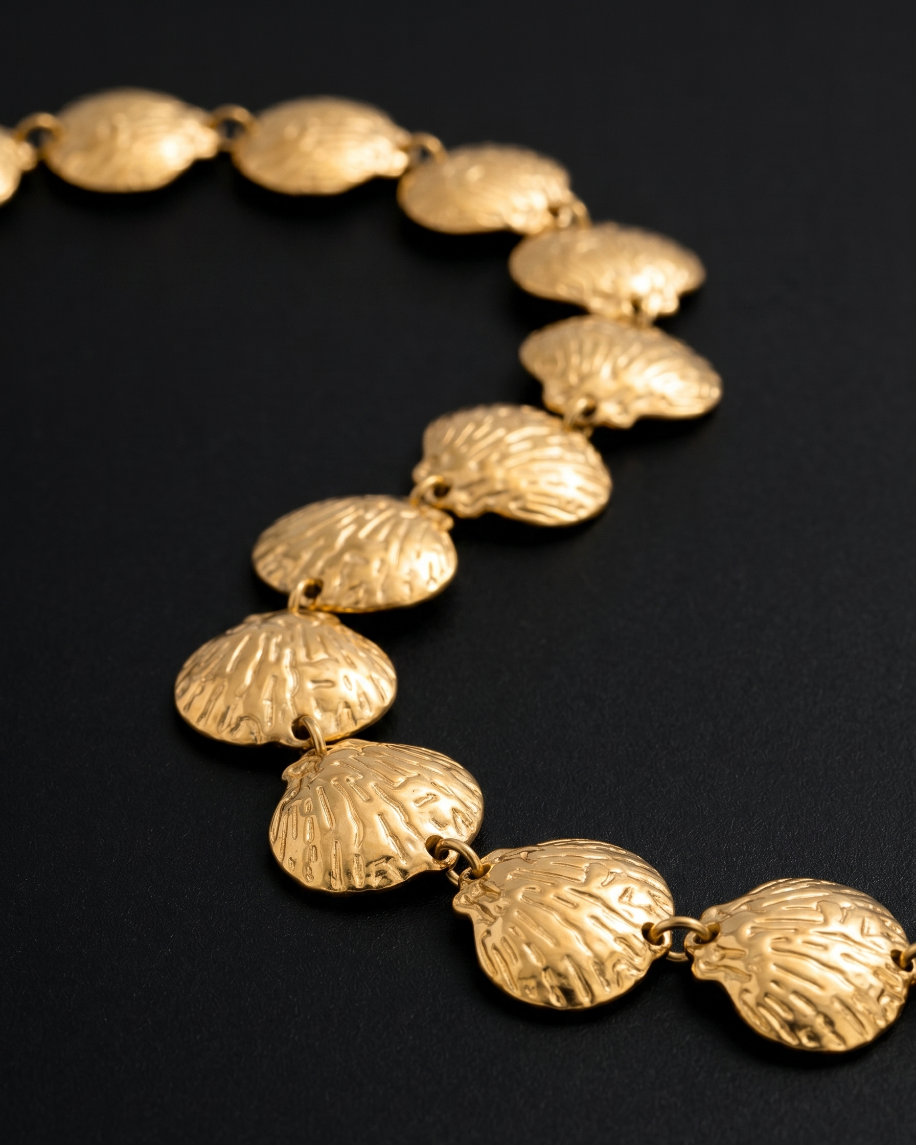 Gold necklace with shell-like links on a black background