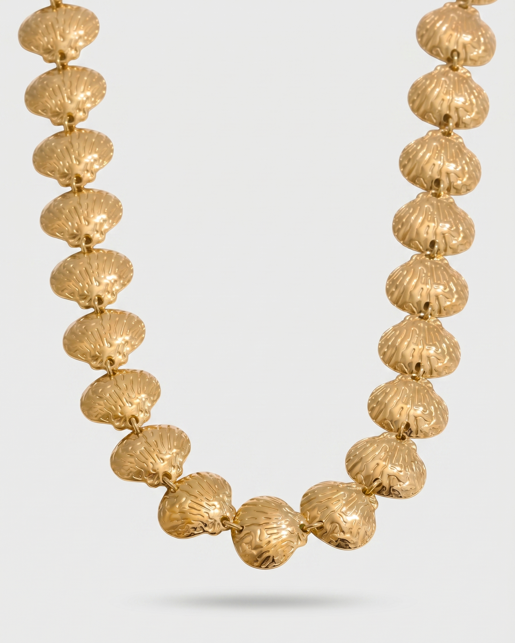 Gold necklace with textured beads on a light gray background