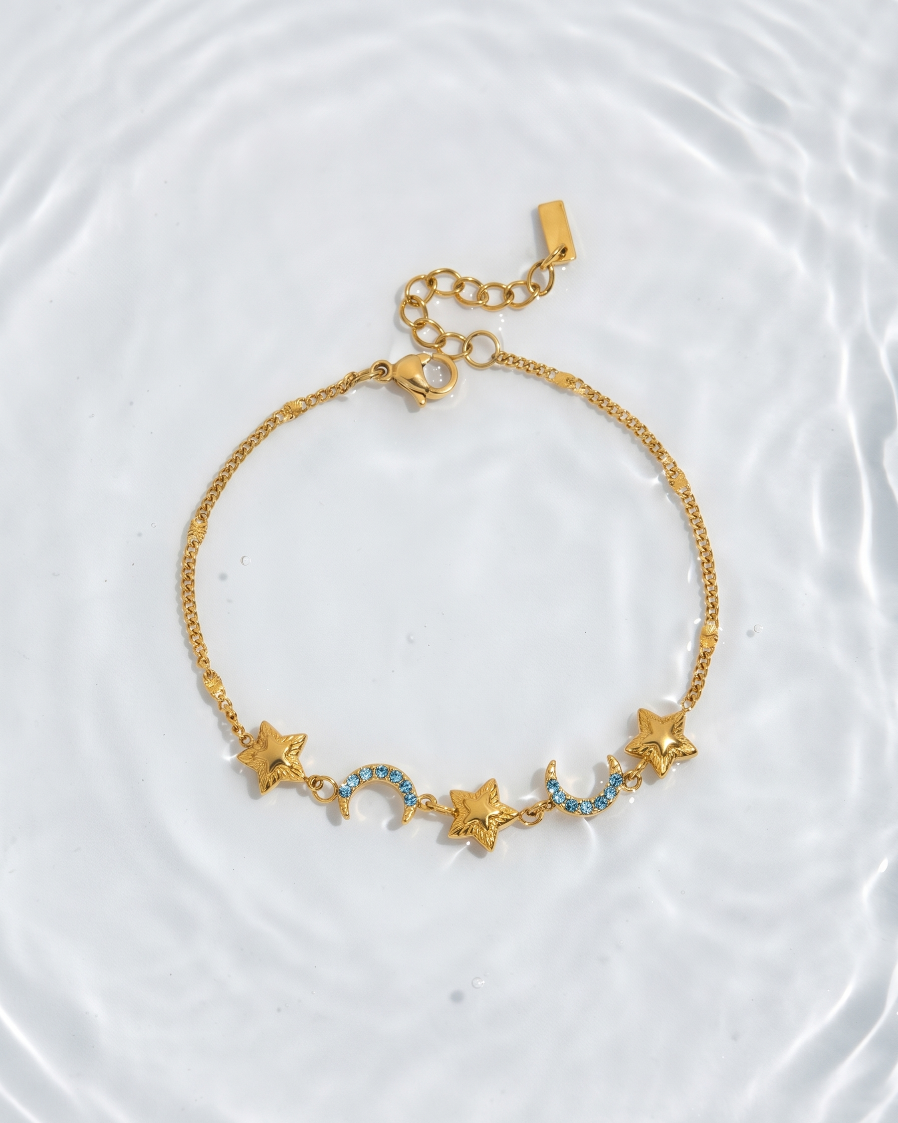 Gold bracelet with star and moon charms on a white background