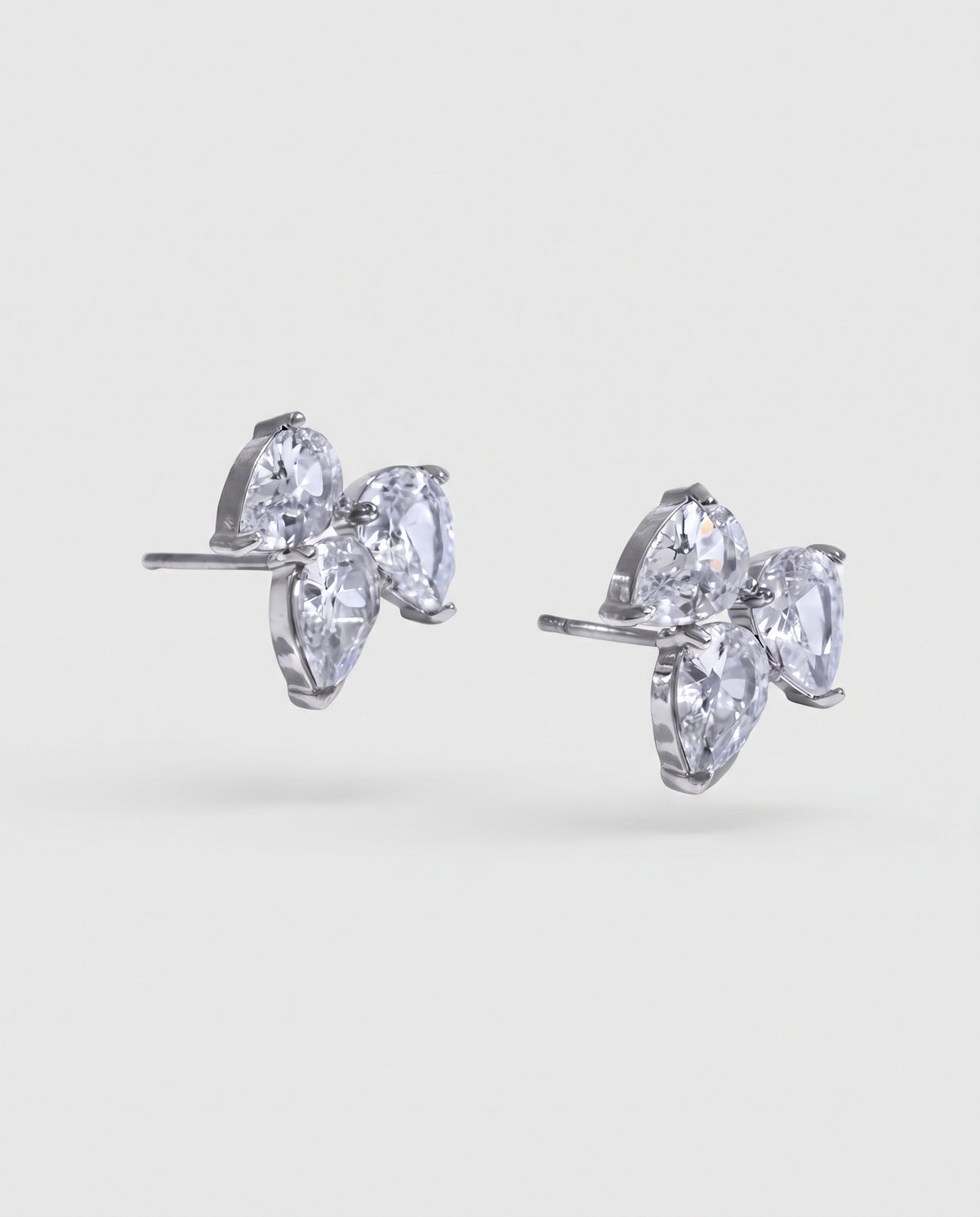 A pair of silver stud earrings featuring three marquise-cut clear gemstones in a flower-like cluster setting, shown on a light gray background.