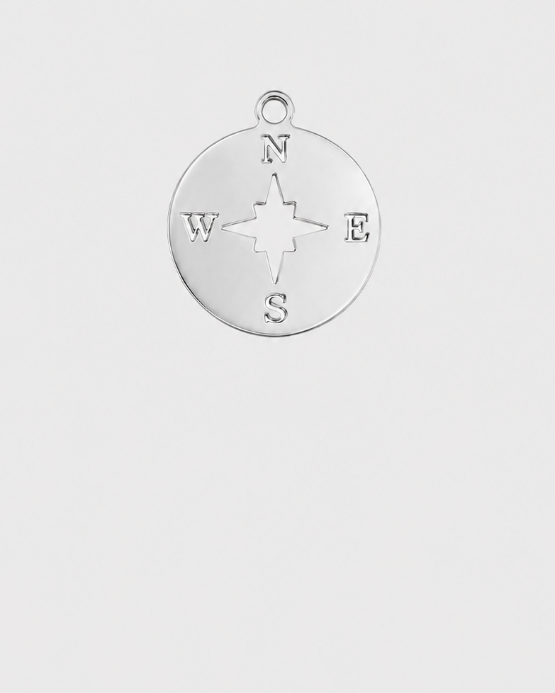 A silver compass-shaped pendant charm with engraved lettering for N, S, E, and W, shown on a light gray background.