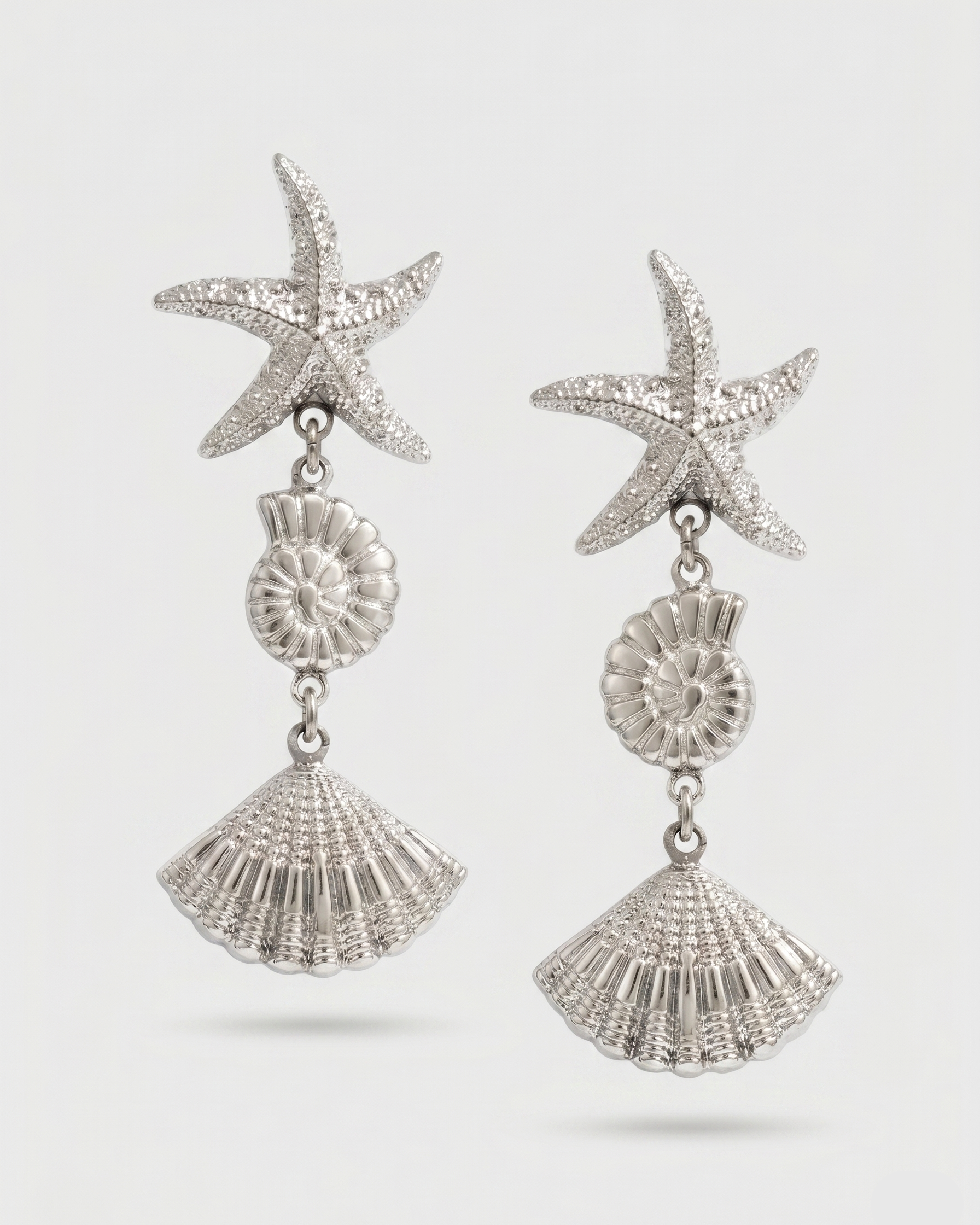 Silver starfish and shell earrings on a white background