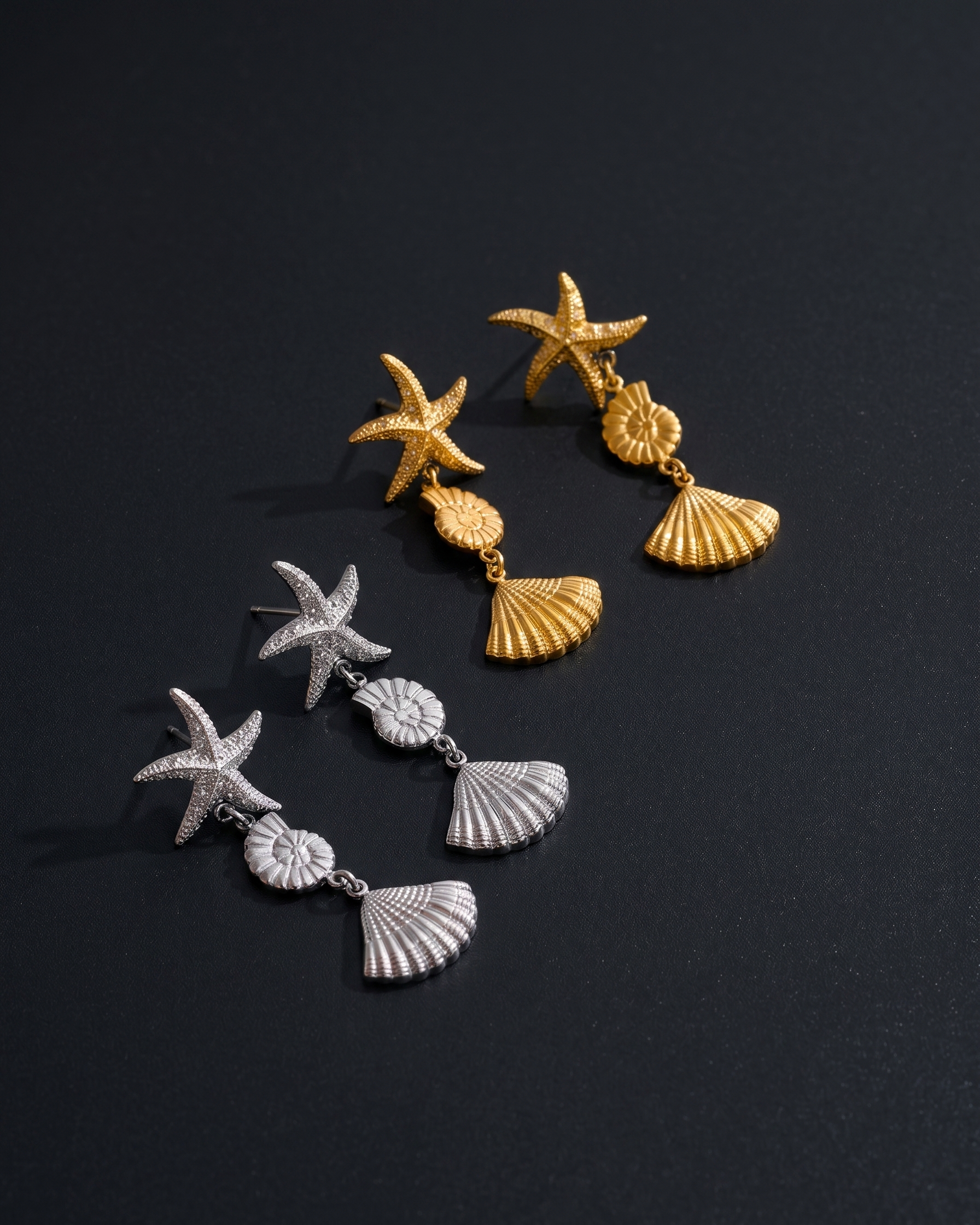 Pair of gold and silver starfish and shell earrings on a black background