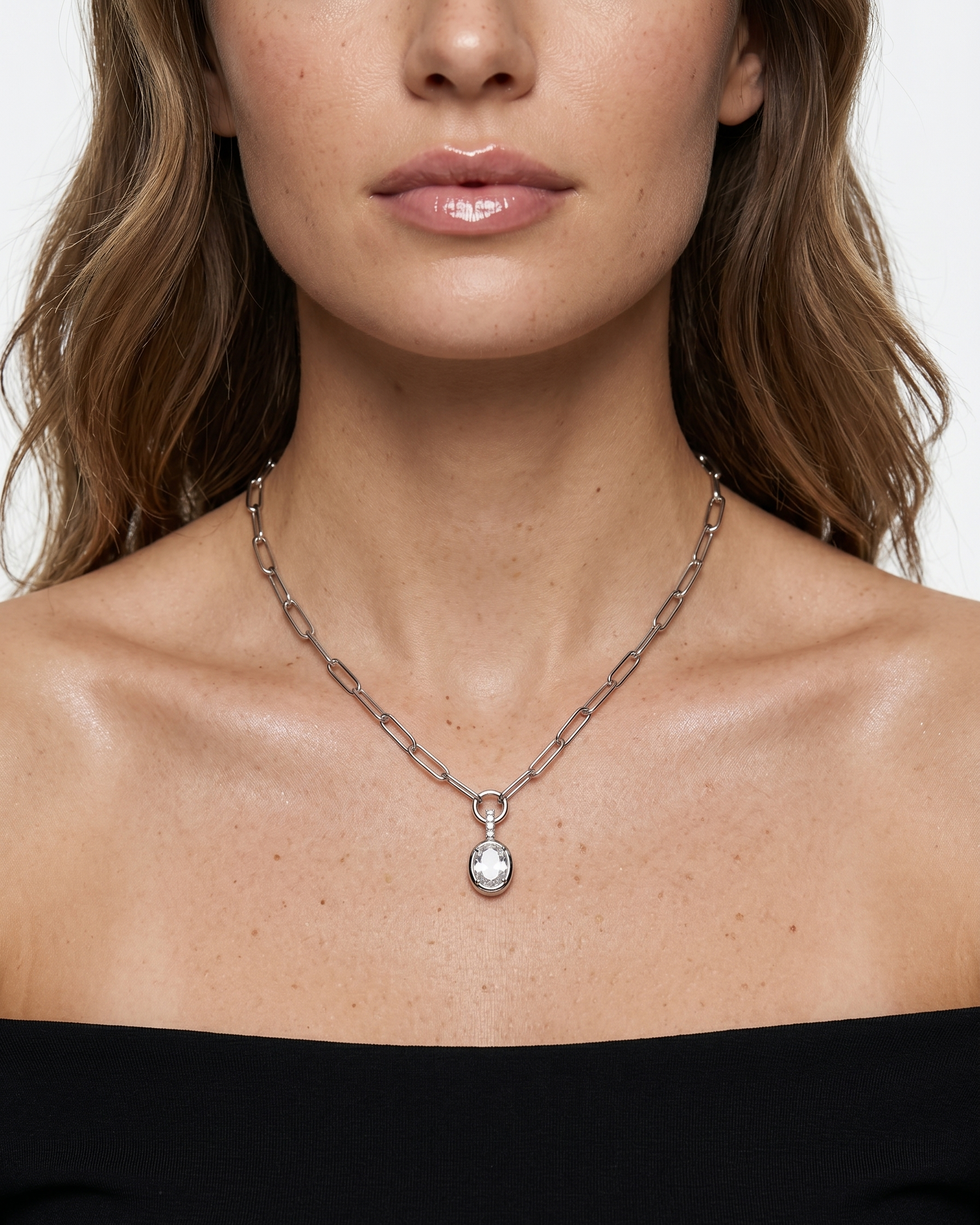Close-up of a woman wearing a silver necklace with a pendant on a white background