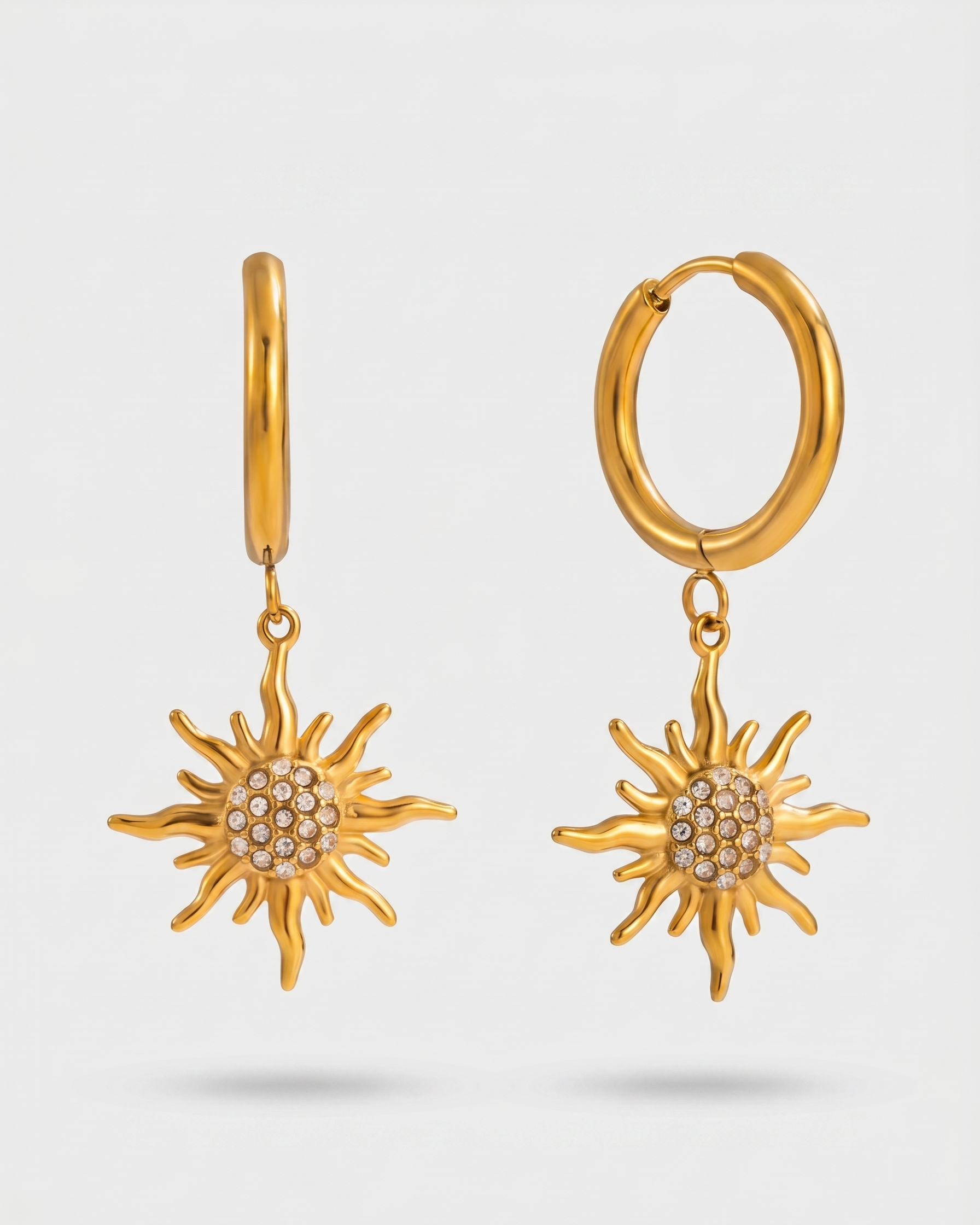 Gold sun-shaped earrings on a light gray background