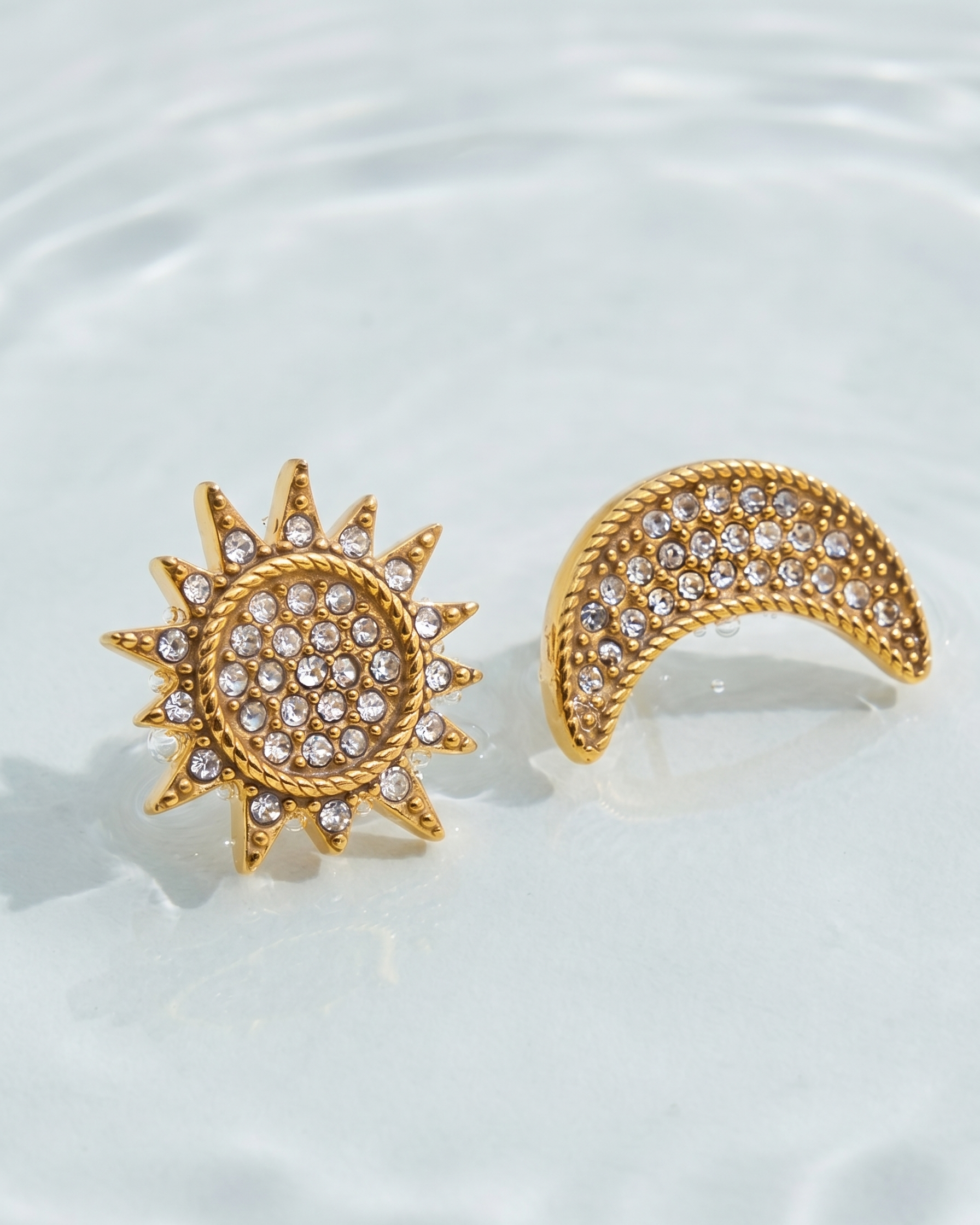 Gold sun and moon earrings with gemstones on a light background