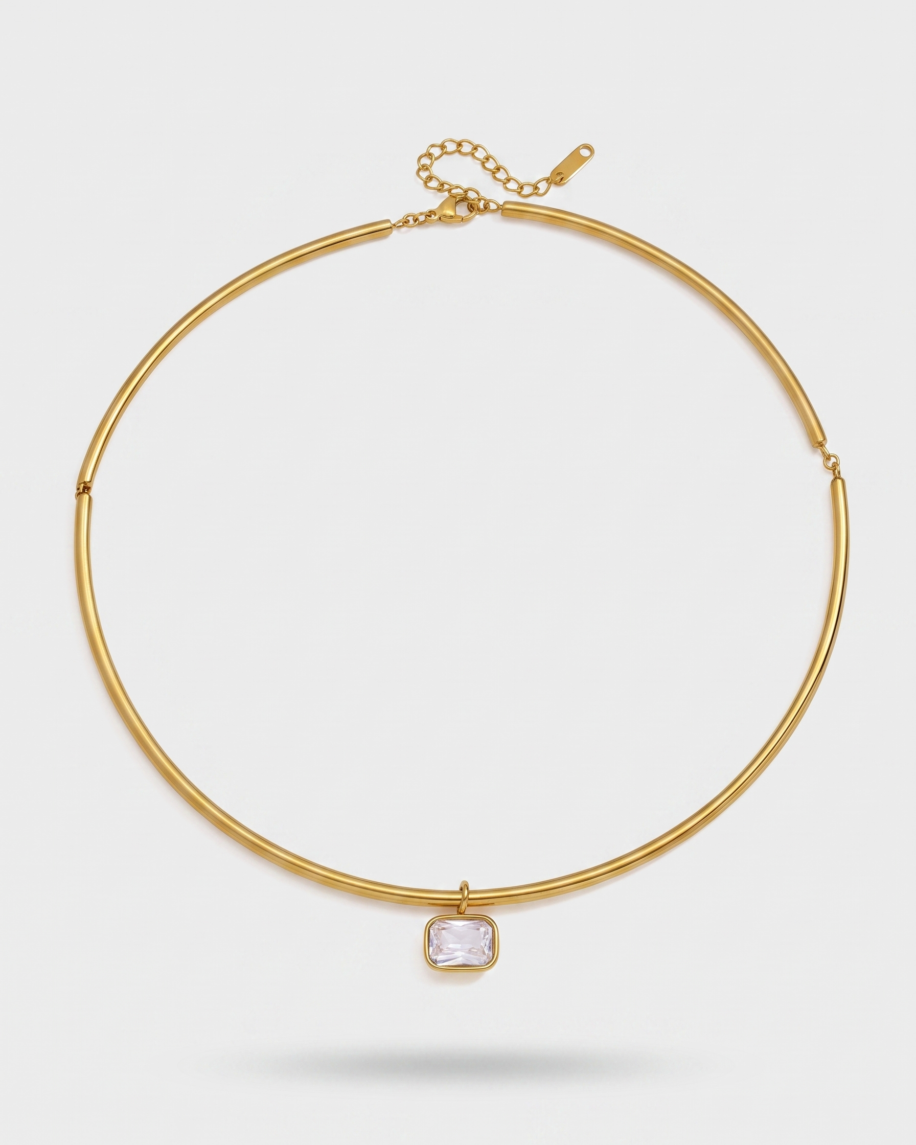 Gold necklace with a clear gemstone on a light gray background