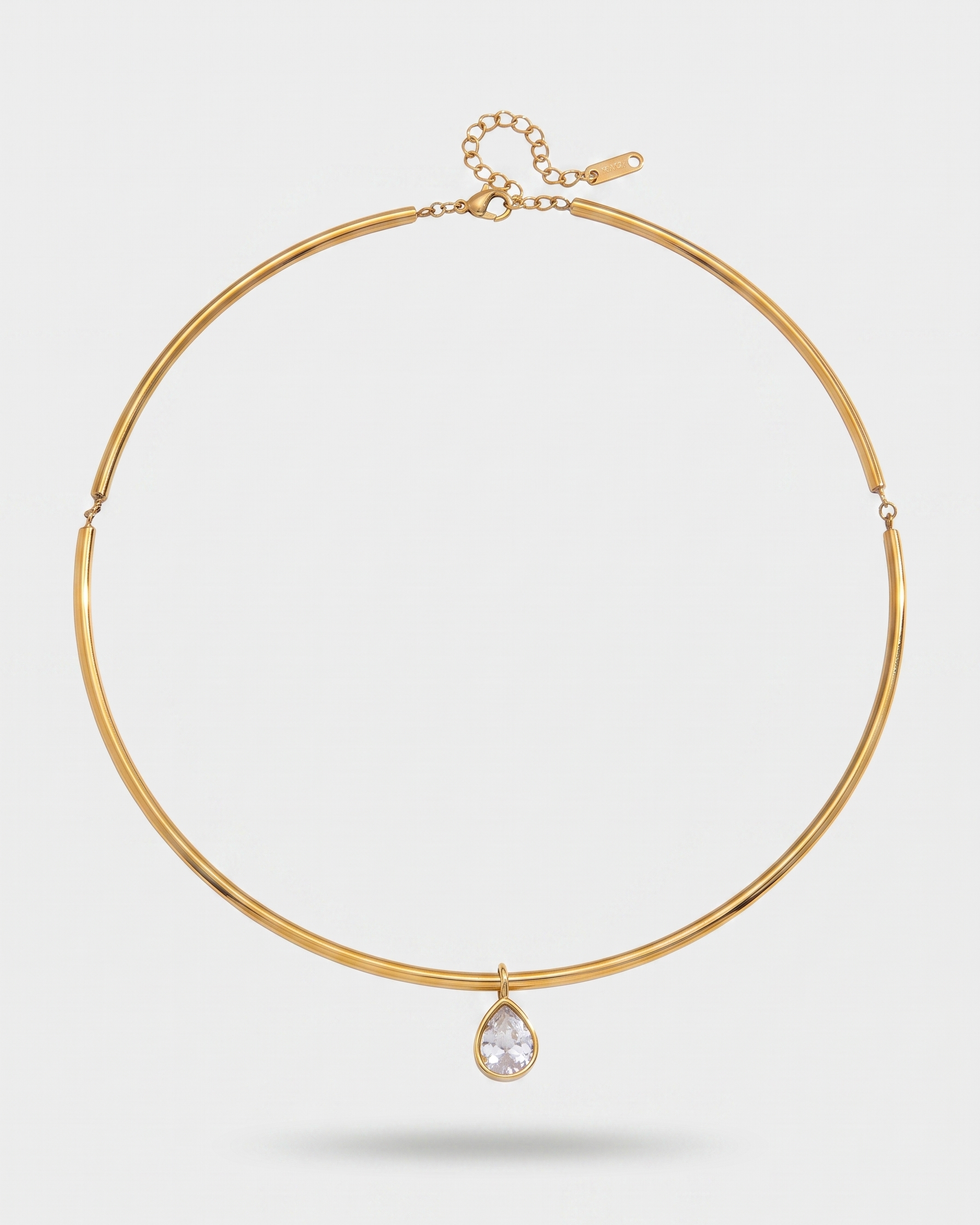 Gold necklace with a teardrop-shaped pendant on a light gray background